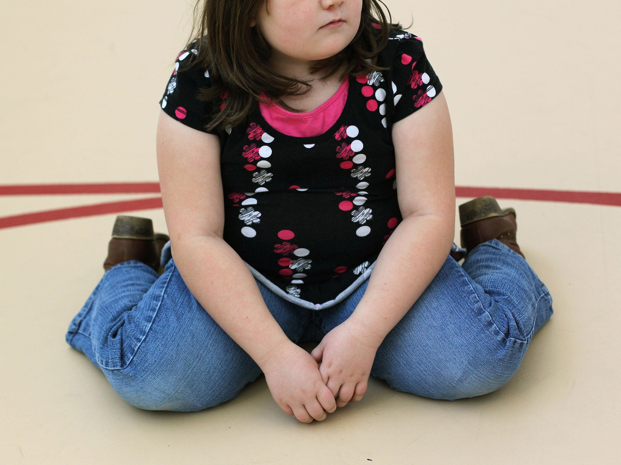A child sits on a gym floor.