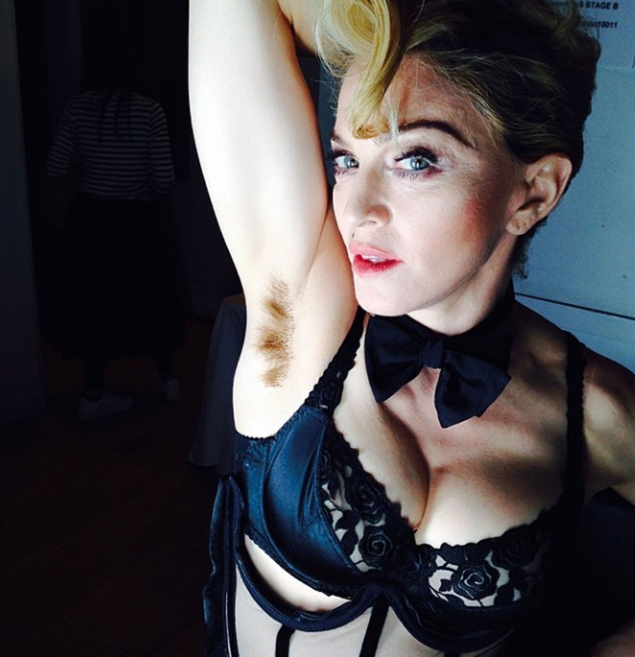 Madonna holds up her right arm to reveal her unshaven armpit
