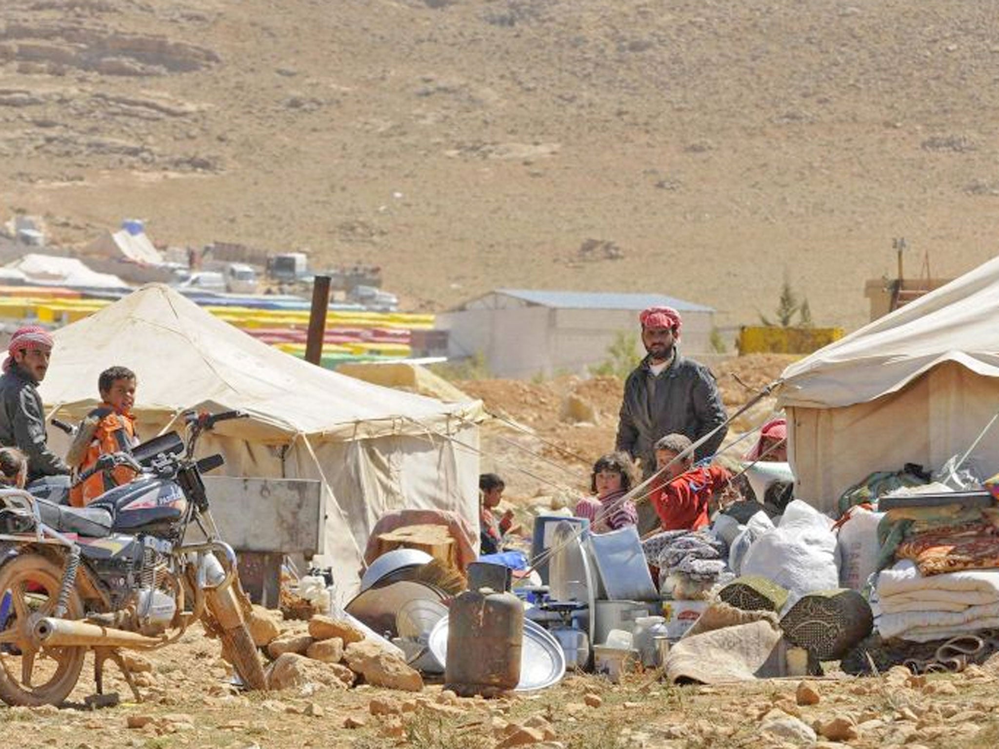 Refugees who fled the violence from the Syrian town of Flita, near Yabroud, stand outside their tents at the border town of Arsal, in the eastern Bekaa Valley. The first of 'several hundred” Syrian refugees to be brought to Britain as part of a Government