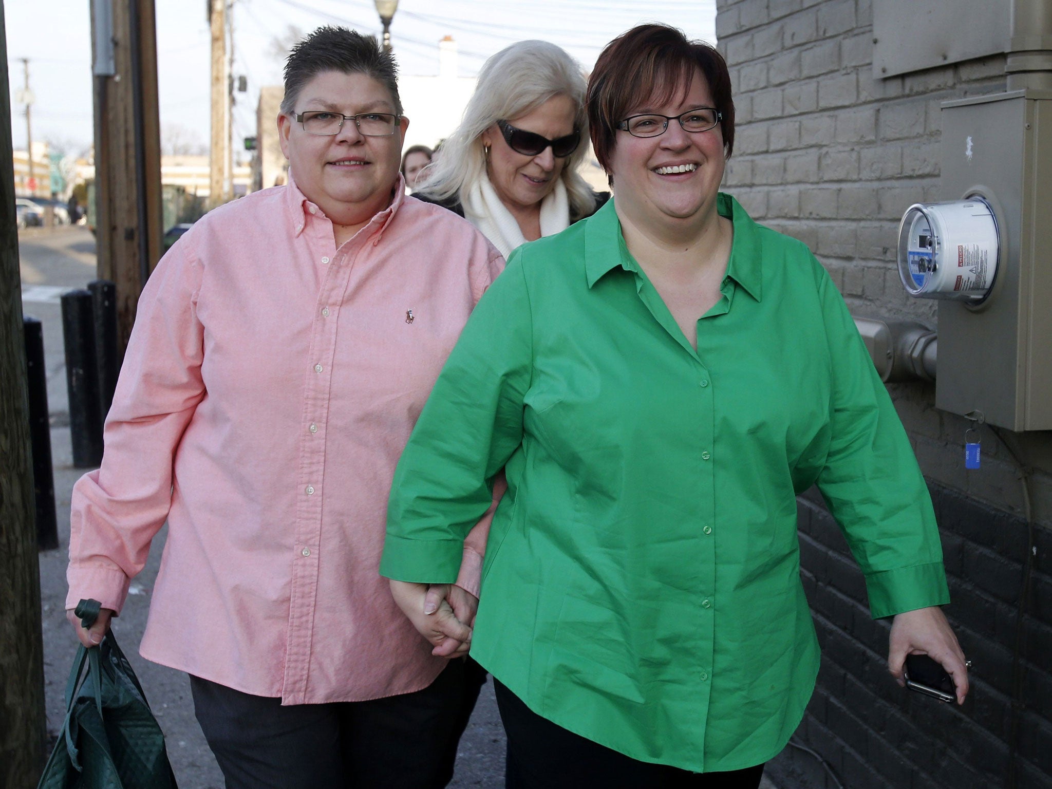Plaintiffs April DeBoer (R) and her partner Jayne Rowse hold hands as they arrive at the Affirmations Center for a news conference after a Michigan federal judge ruled that a ban on same-sex marriage violates the U.S. Constitution and must be overturned,
