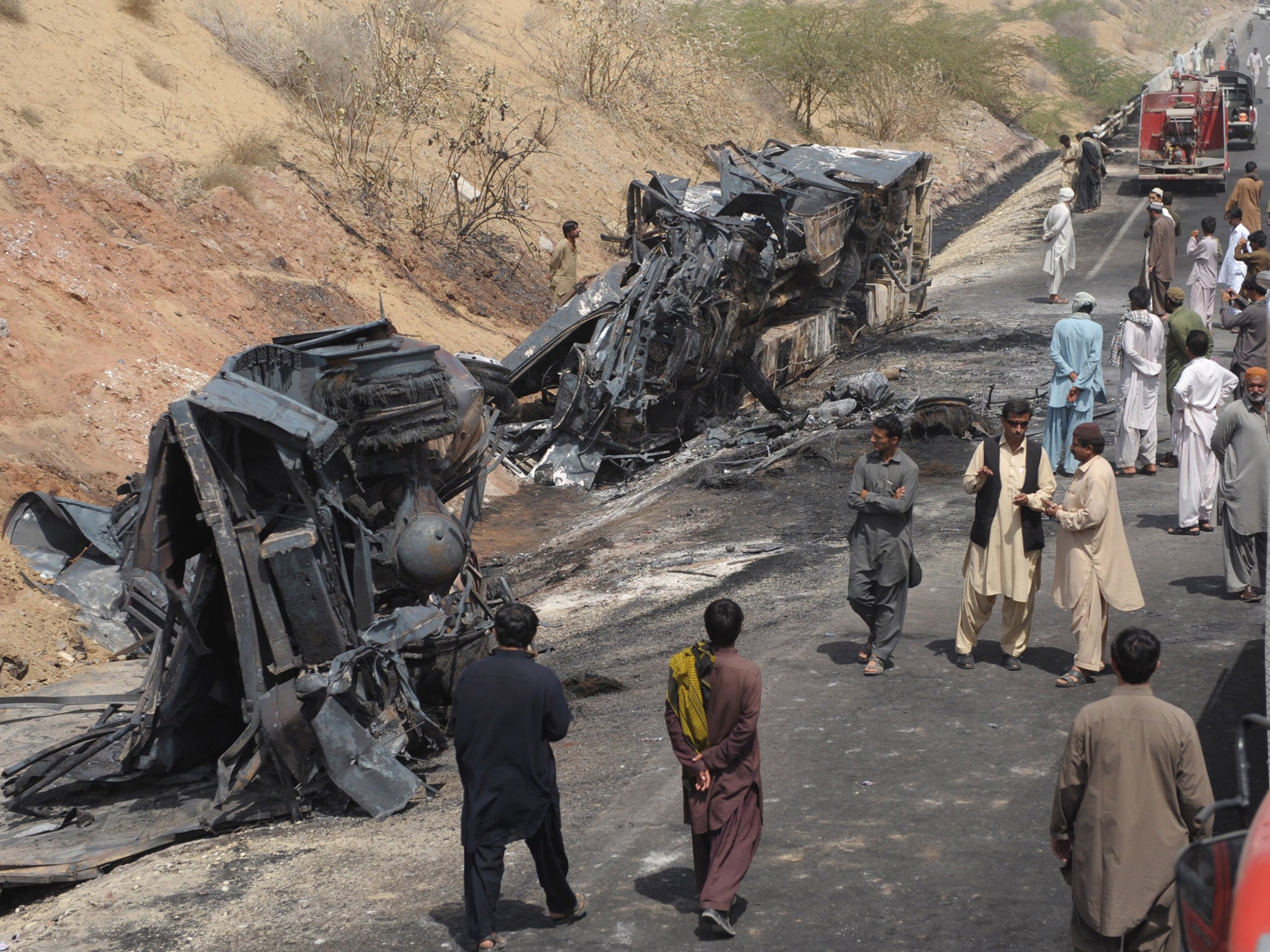 Pakistani onlookers gather near burnt vehicle wreckage in Hub, near Gadani district of Baluchistan province on March 22, 2014