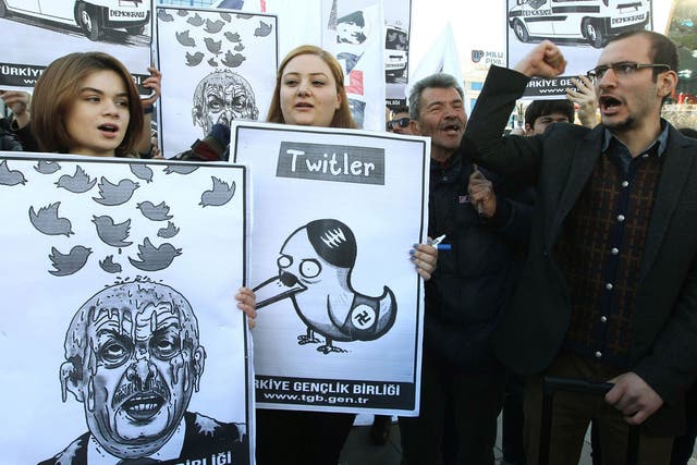 People hold placards as they protest against Turkey's Prime Minister Tayyip Erdogan after the government blocked access to Twitter