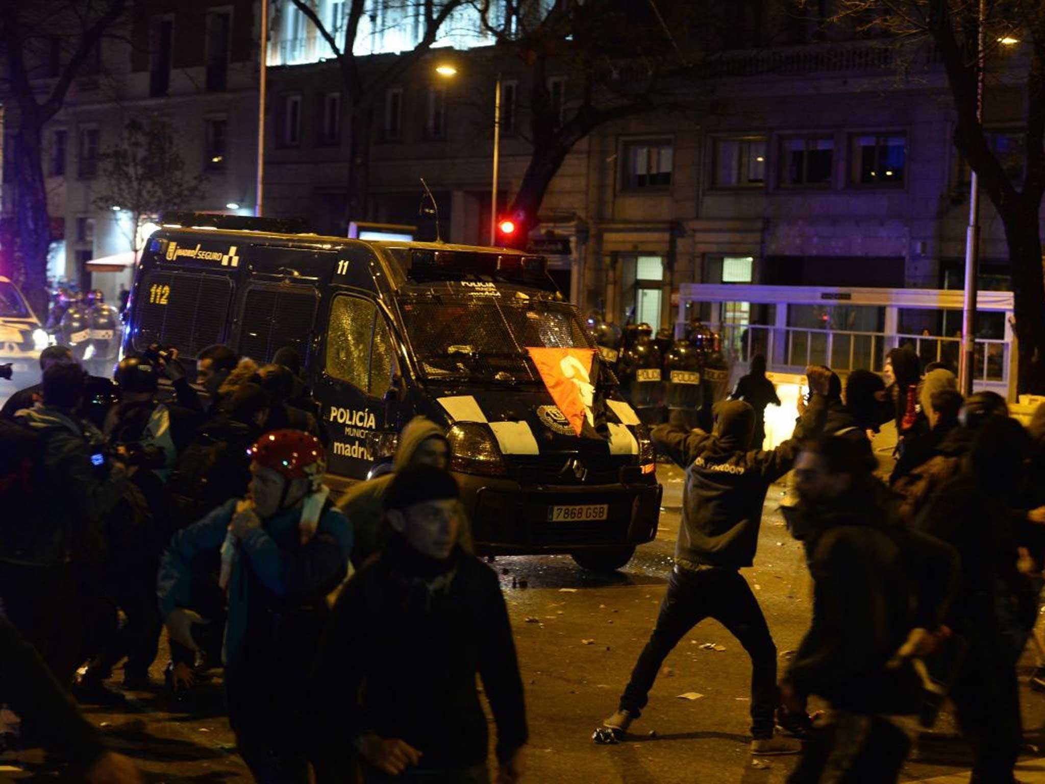 Demonstrators throw projectiles at a police van during clashes at the end of a march dubbed "the Marches for Dignity 22-M"