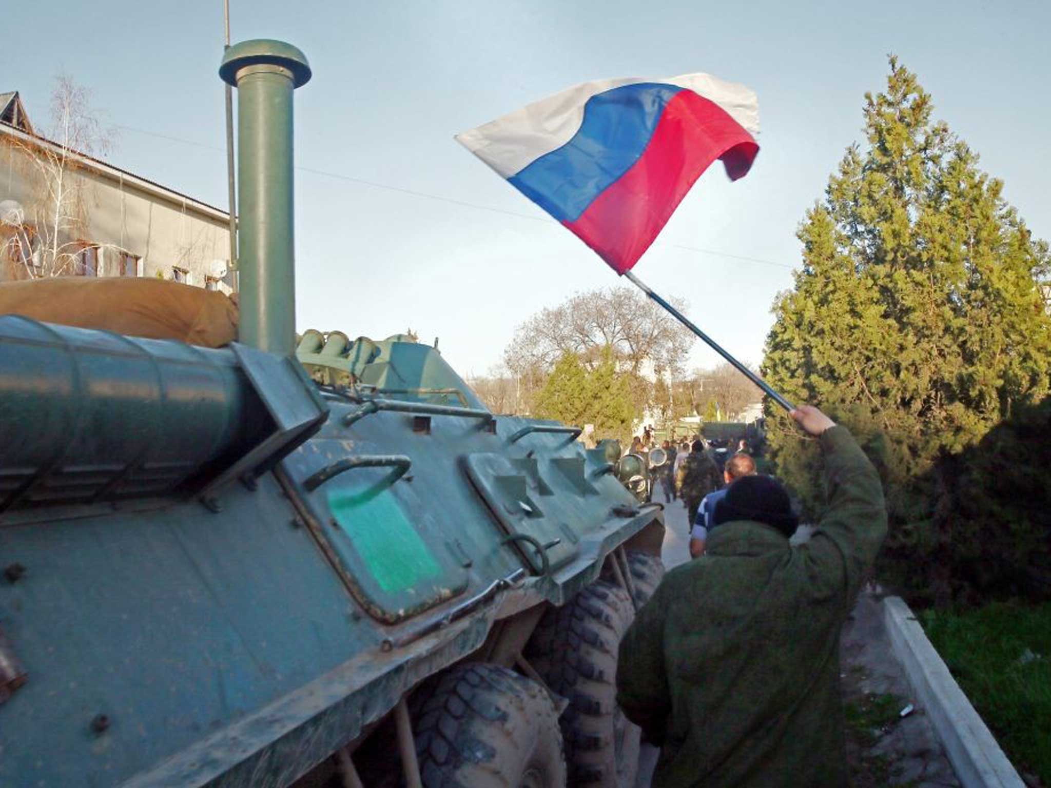 A member of the Pro-Russian Self Defence Forces raises the Russian flag as the base is stormed