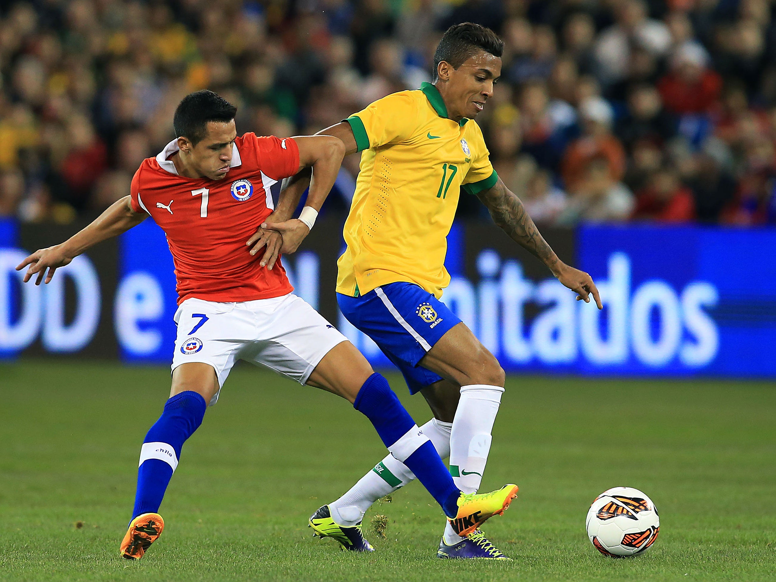 Luiz Gustavo of Brazil tussling with Chile's Alexis Sanchez