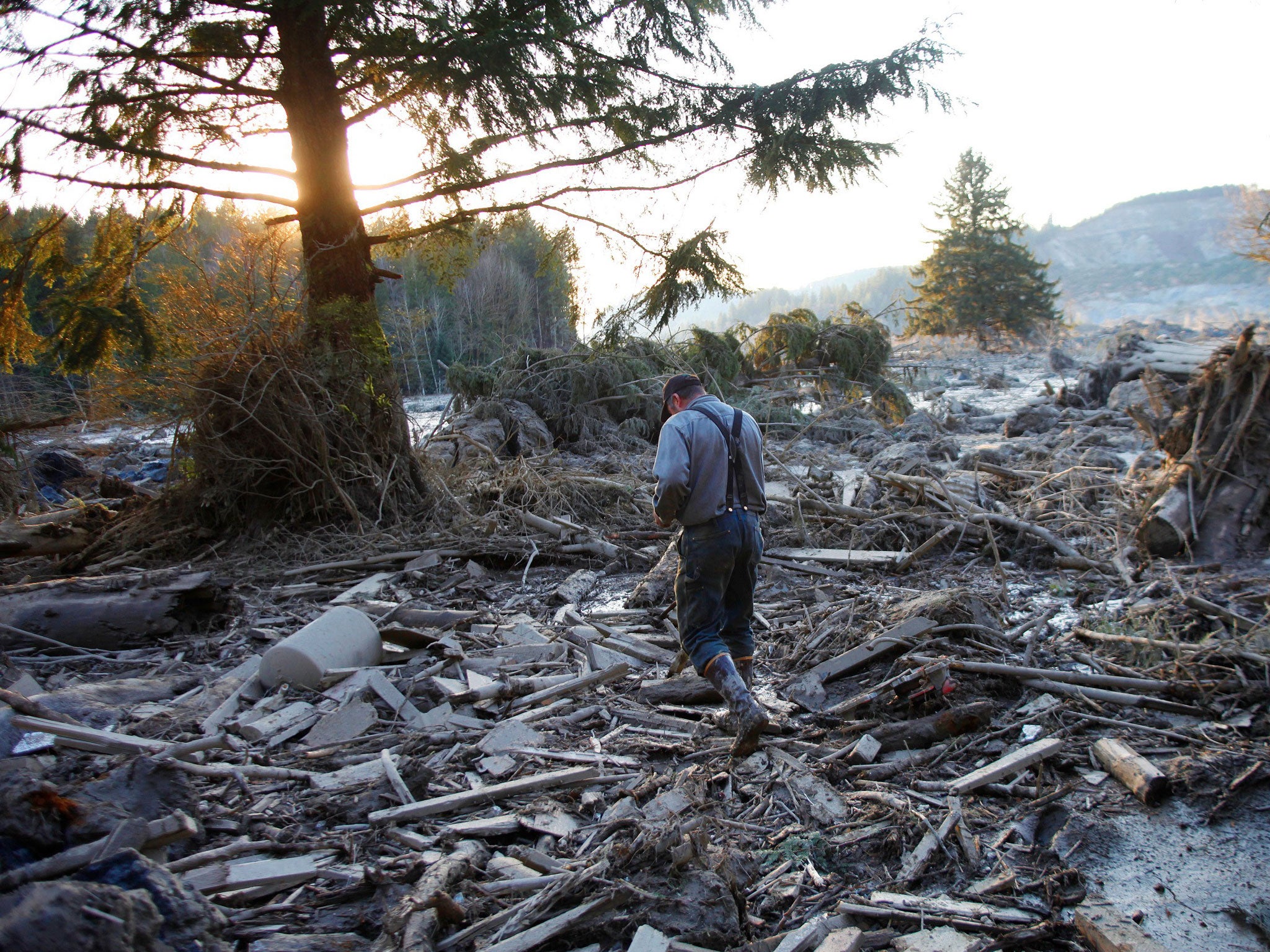 Steve Skaglund walks across the rubble on the east side of Saturday's fatal mudslide near Oso, Wash., Sunday, March 23