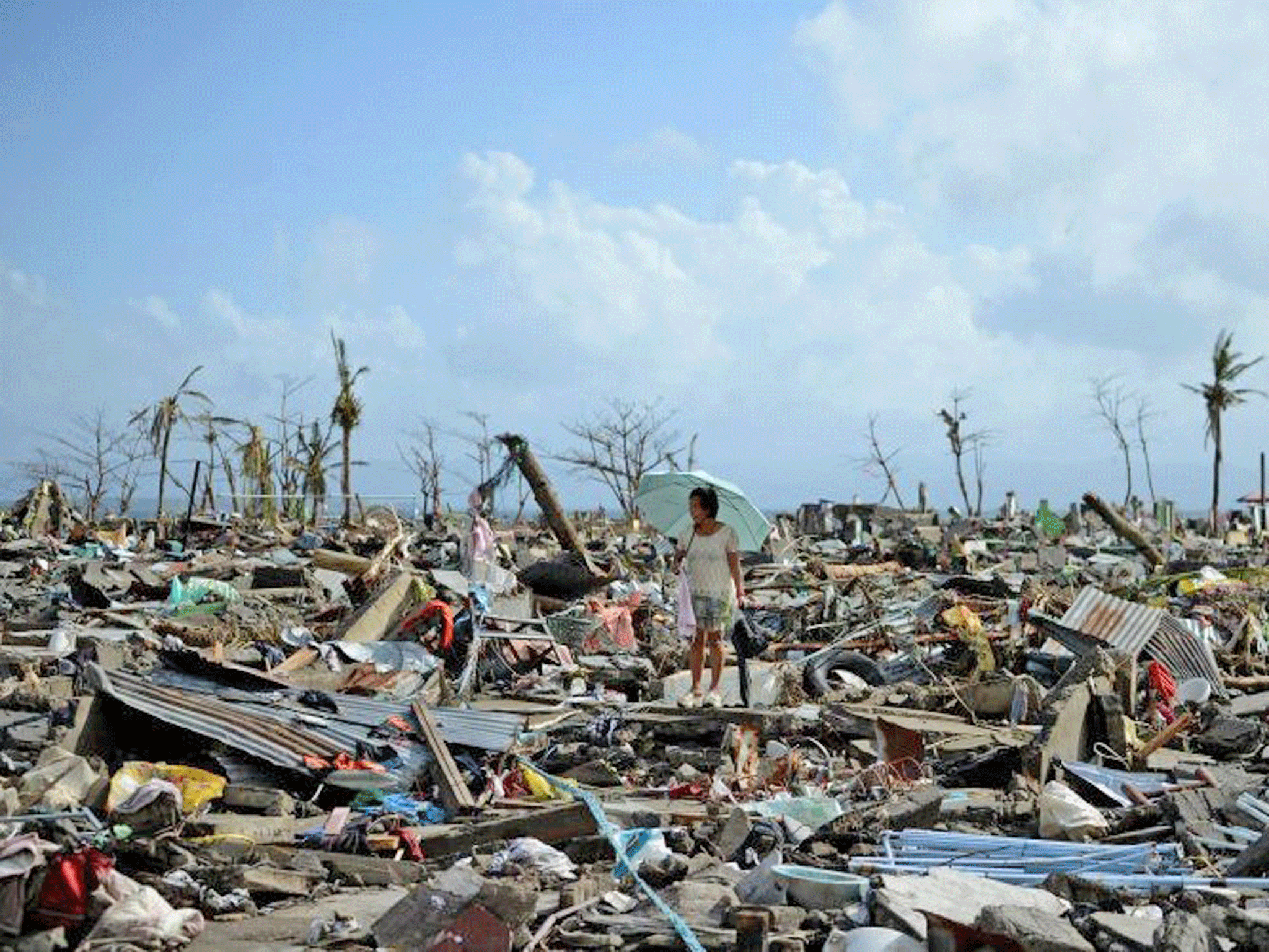 A survivor walks among the debris of houses destroyed by Super Typhoon Haiyan in Tacloban in the eastern Philippine island of Leyte on November 11, 2013