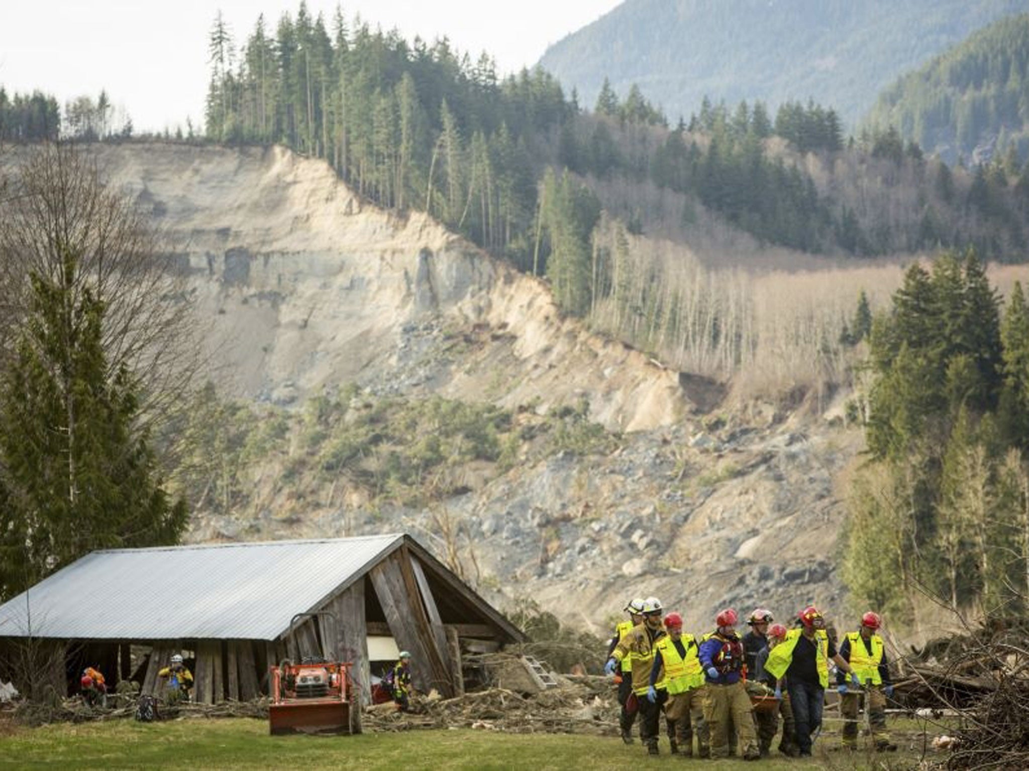 Rescue workers remove one of a number of bodies from the wreckage of homes destroyed by a mudslide near Oso