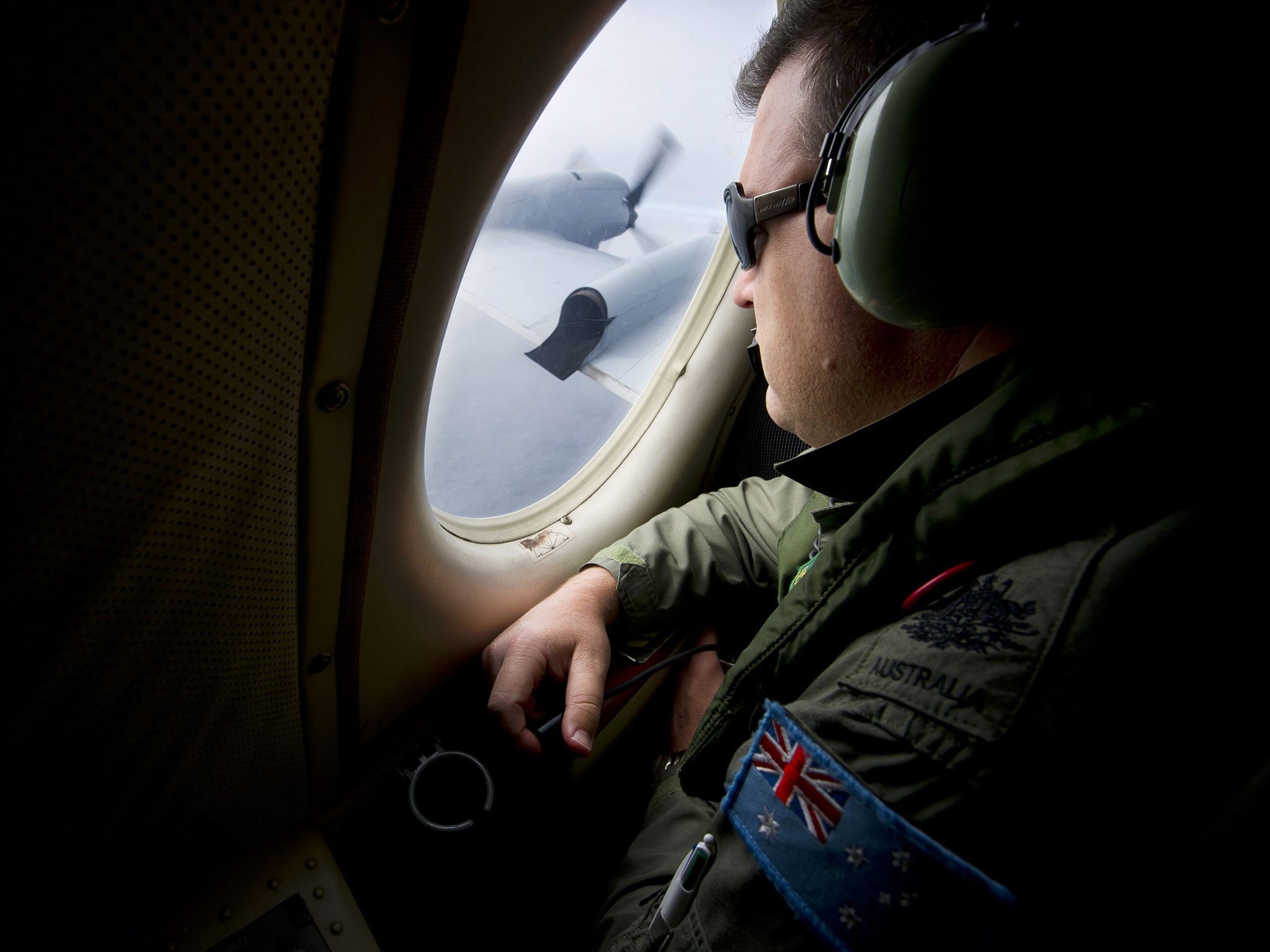 Royal Australian Air Force (RAAF) airborne electronics analyst Warrant Officer Nicholas Harding scans the southern Indian Ocean from the observation window of an AP-3C Orion aircraft