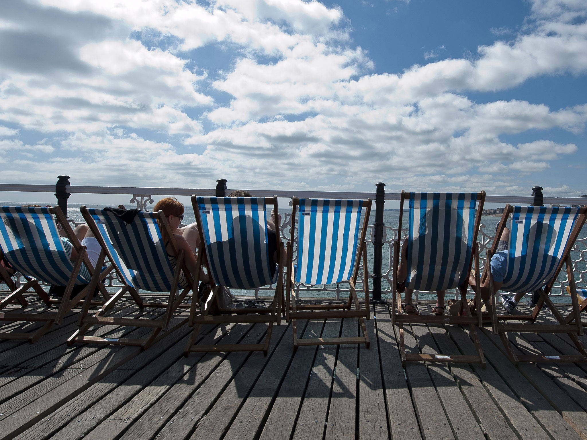 People relax in deckchairs on Brighton Pier in Brighton, on the south coast during hot weather on July 20th, 2013