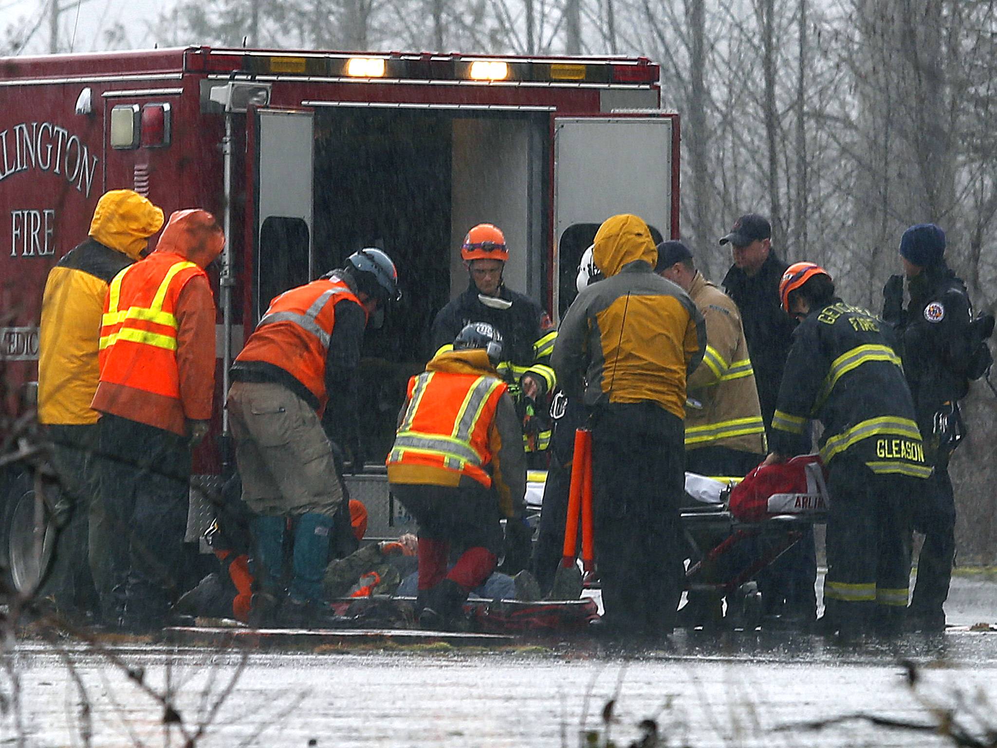 A helicopter and waiting ground crew transfer an injured worker into an ambulance