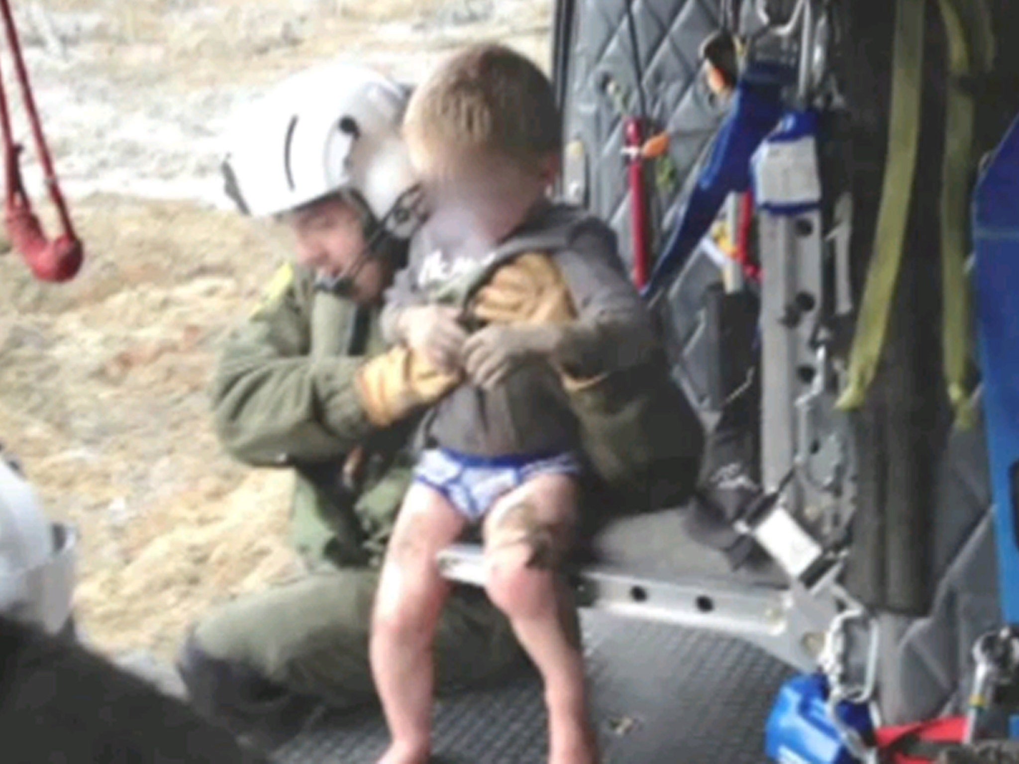 A helicopter rescuer snatches a four-year-old boy from the mudslide
