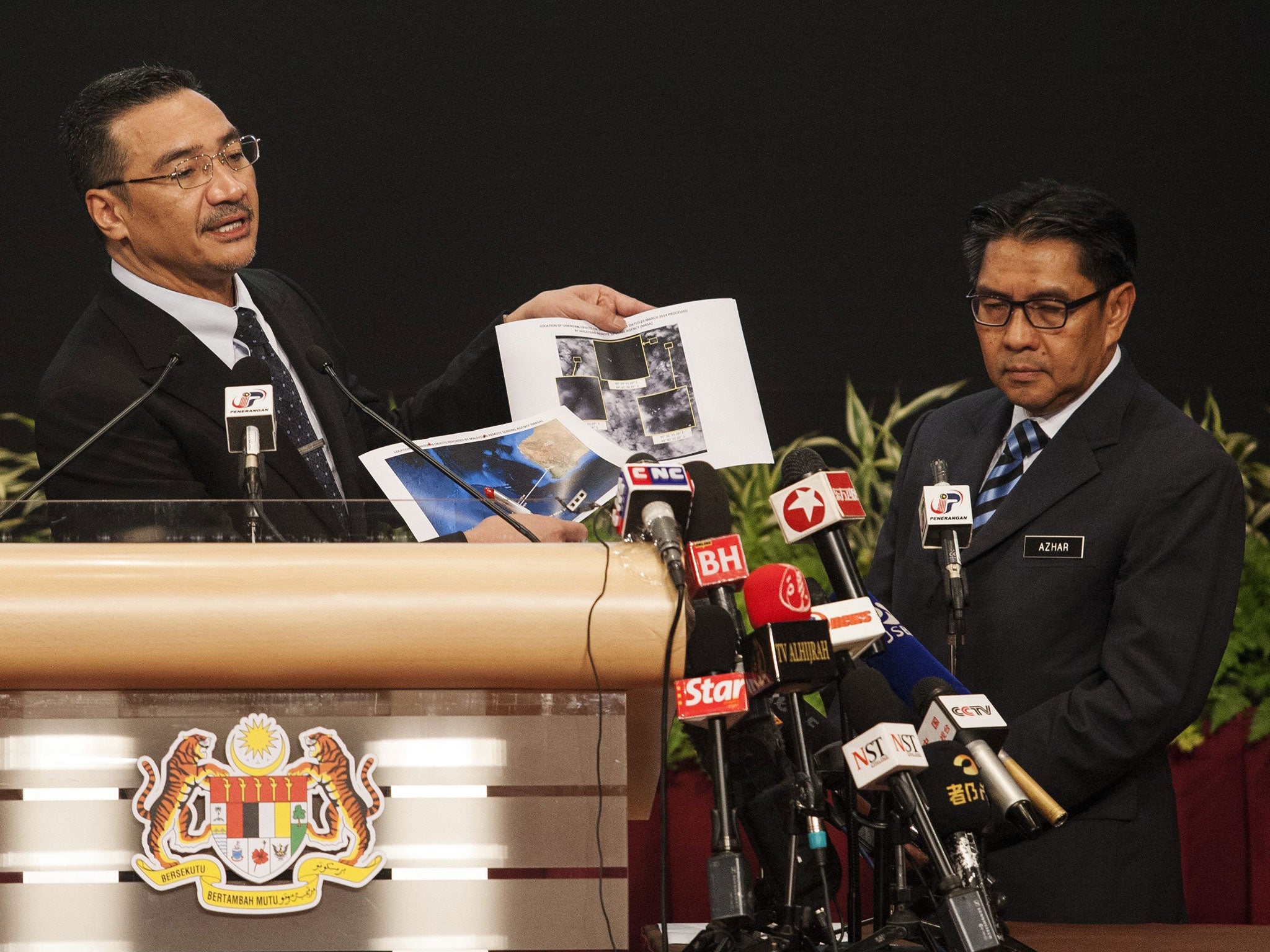 Malaysian Defense Minister and acting Transport Minister Hishammuddin Hussein (L) and Malaysia's Department Civil Aviation Director General, Azharuddin Abdul Rahman (R) show pictures of possible debris during a media conference in Kuala Lumpur
