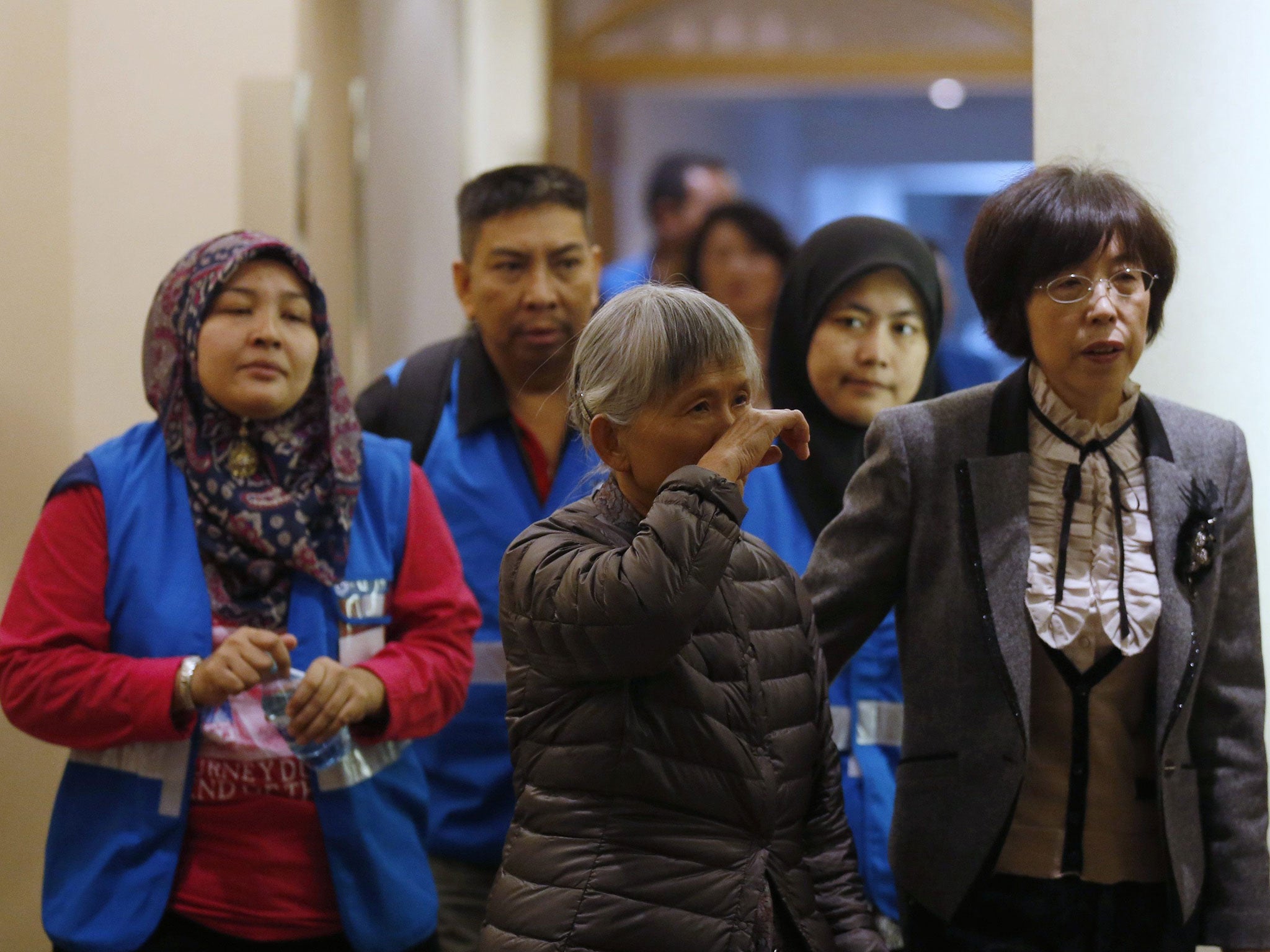 A relative (centre) of a passenger aboard Malaysia Airlines MH370 attends a meeting with volunteers from Malaysia (in blue vests) at the Lido Hotel in Beijing, 27 March, 2014