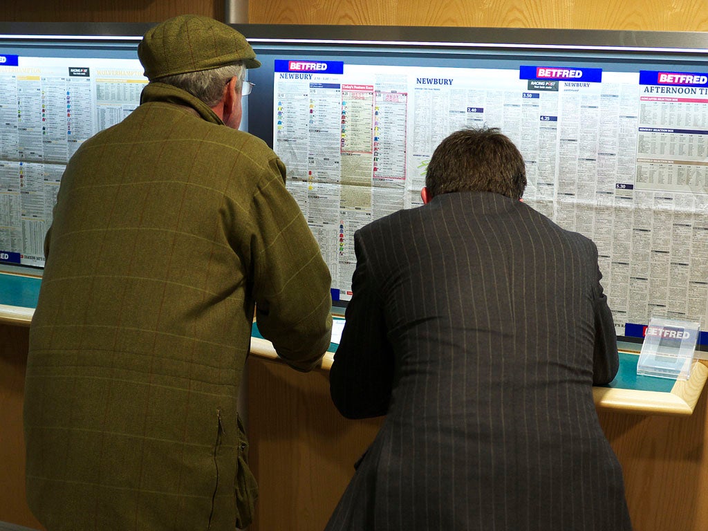 Racegoers stay out of the rain and check out the form in the betting shop at Newbury racecourse on March 22, 2013 in Newbury, England.