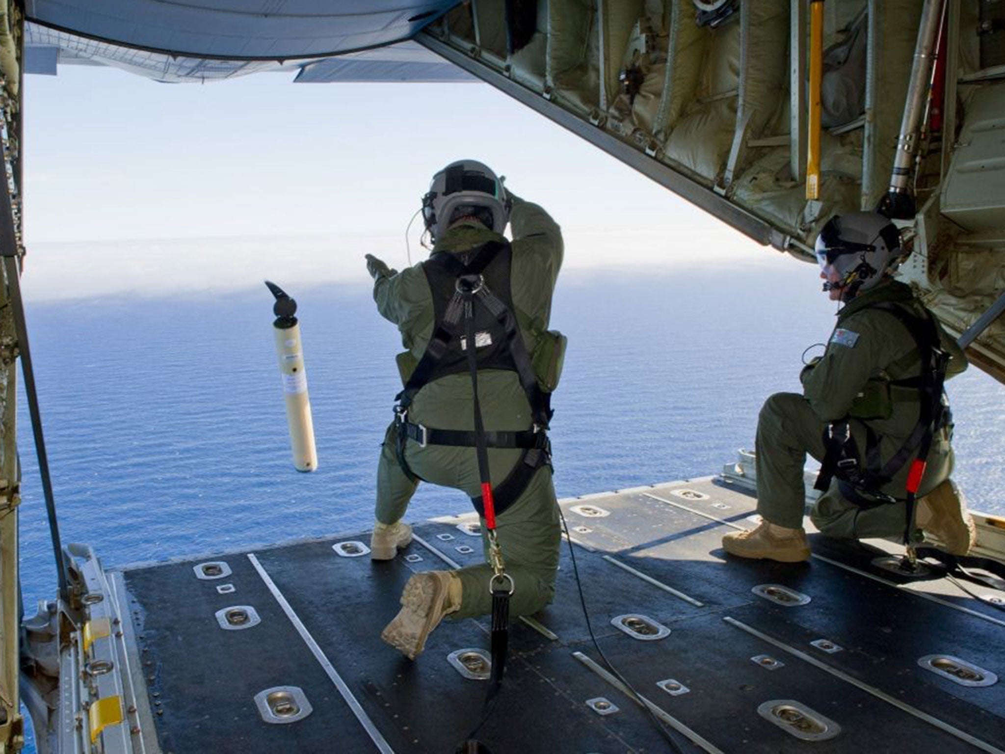 Royal Australian Air Force Loadmasters Sgt. Adam Roberts, left, and Flight Sgt. John Mancey, launch a Self Locating Data Marker Buoy from a C-130J Hercules aircraft in the southern Indian Ocean as part of the Australian Defence Force's assistance to the s