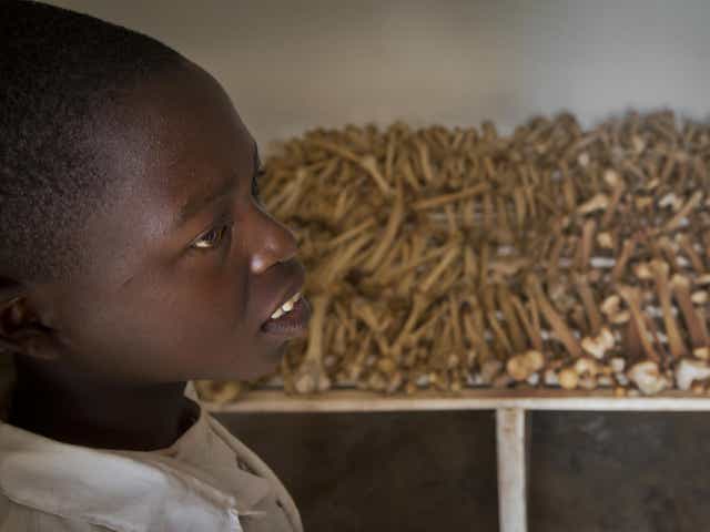 Nikeyimana Obadia, 12, who lives nearby, stands by rows of human bones that form a memorial to those who died in the redbrick church that was the scene of a massacre during the 1994 genocide, in the village of Nyarubuye, eastern Rwanda