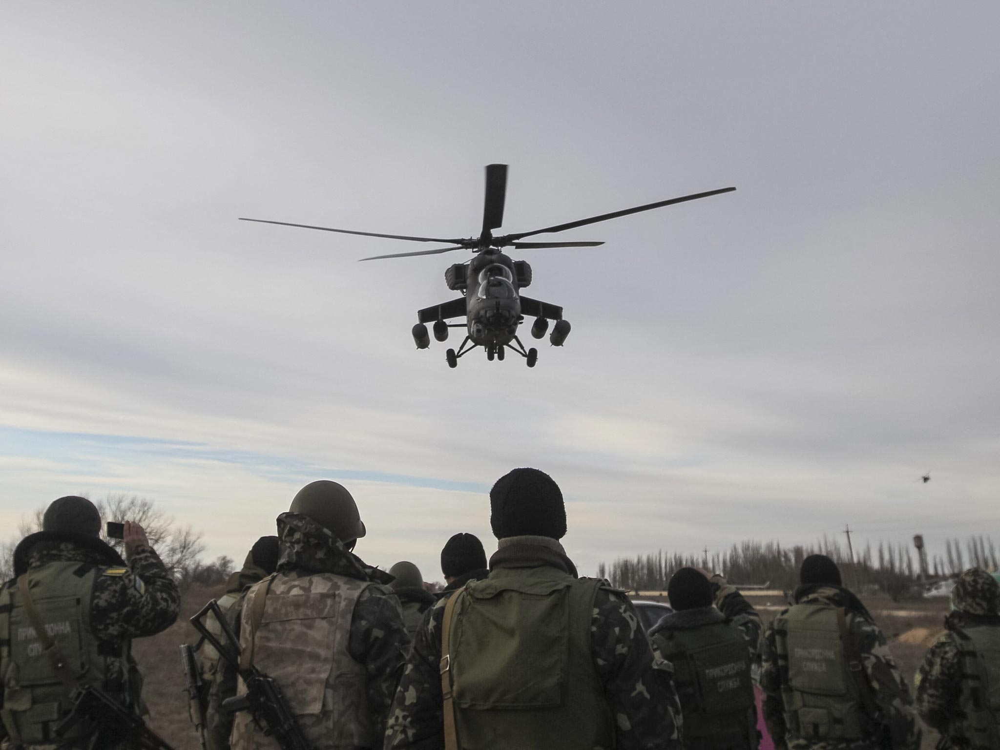 A Russian army MI-35 military helicopter patrols the area as Ukrainian servicemen guard a checkpoint near the village of Strelkovo in Kherson region adjacent to Crimea