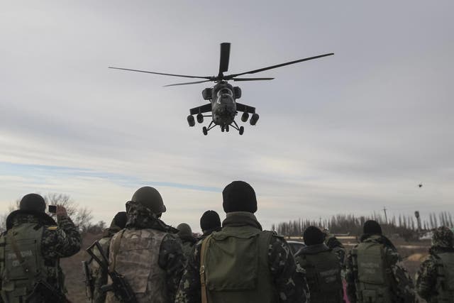 A Russian army MI-35 military helicopter patrols the area as Ukrainian servicemen guard a checkpoint near the village of Strelkovo in Kherson region adjacent to Crimea