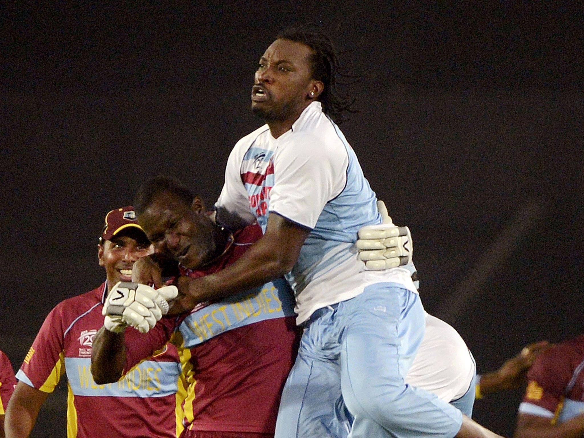 Chris Gayle leaps on top of Darren Sammy after running on to the pitch to celebrate West Indies’ win over Australia