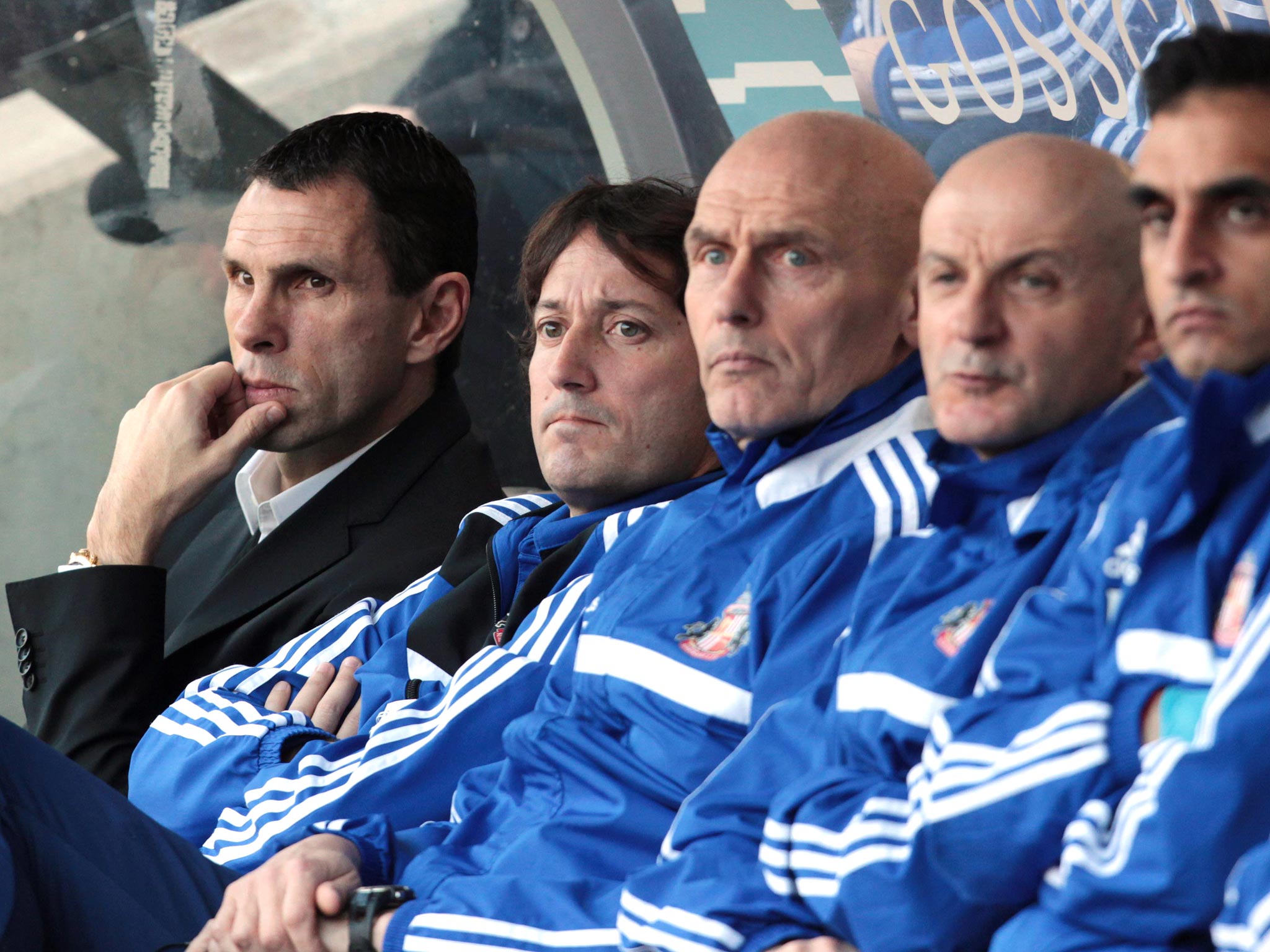 Gus Poyet sits in the dugout alongside his coaching staff