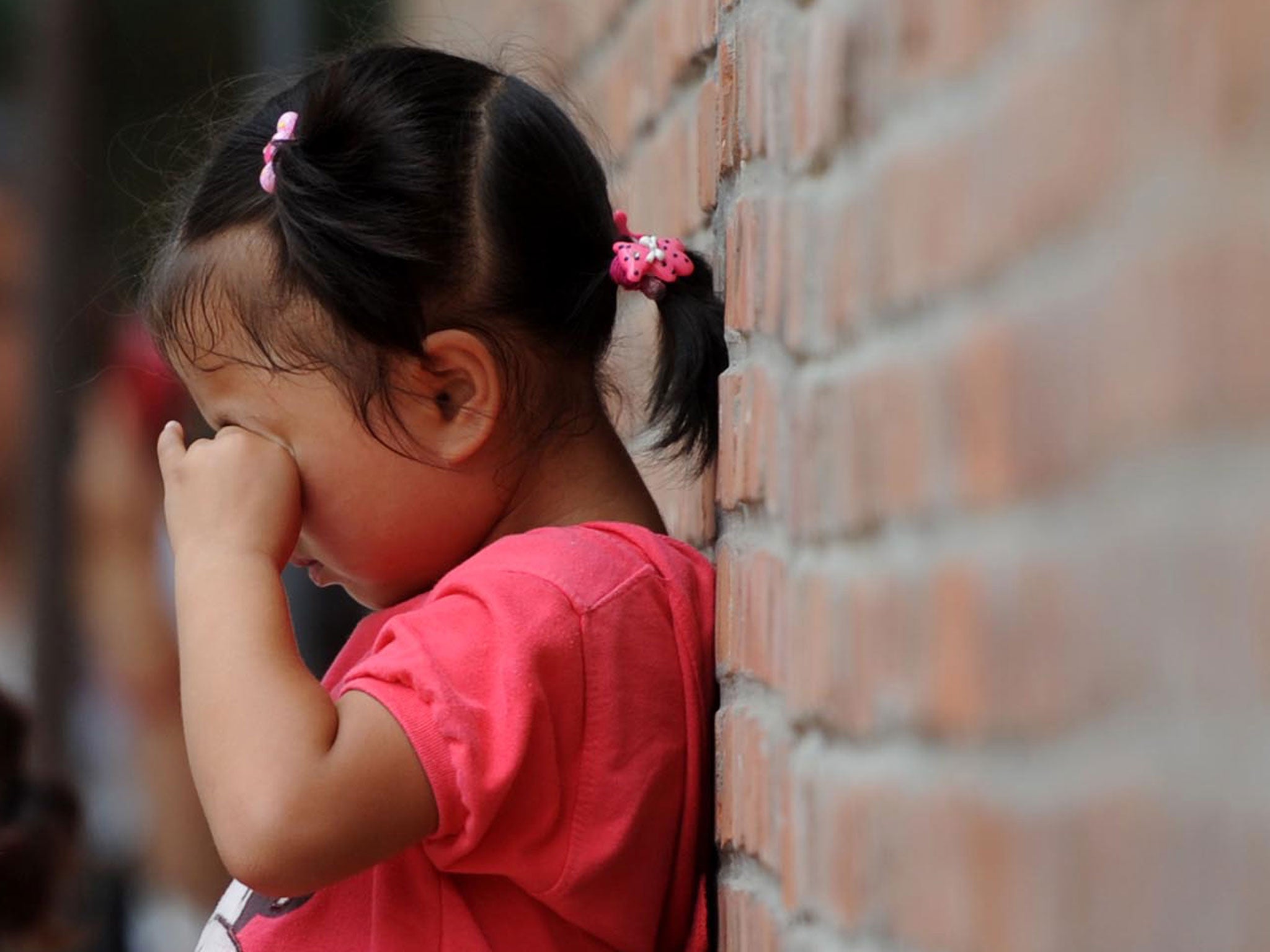 A child cries against a wall (image posed by model)