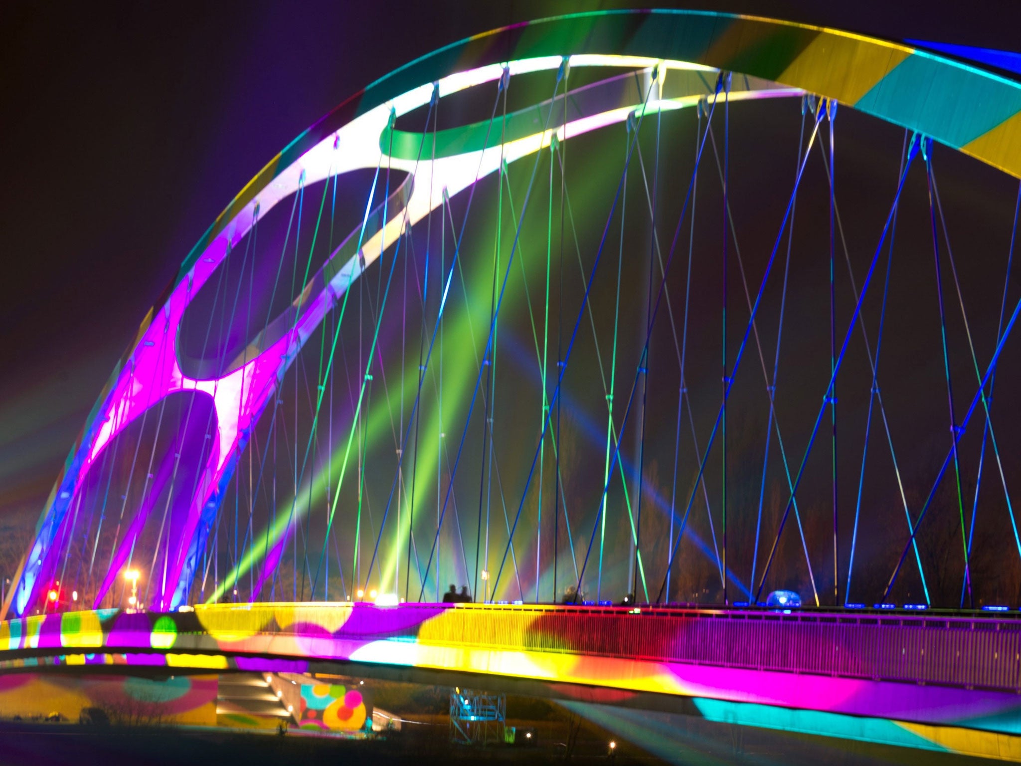 People crosses the illuminated bridge Osthafenbruecke during Luminale festival of light in Frankfurt