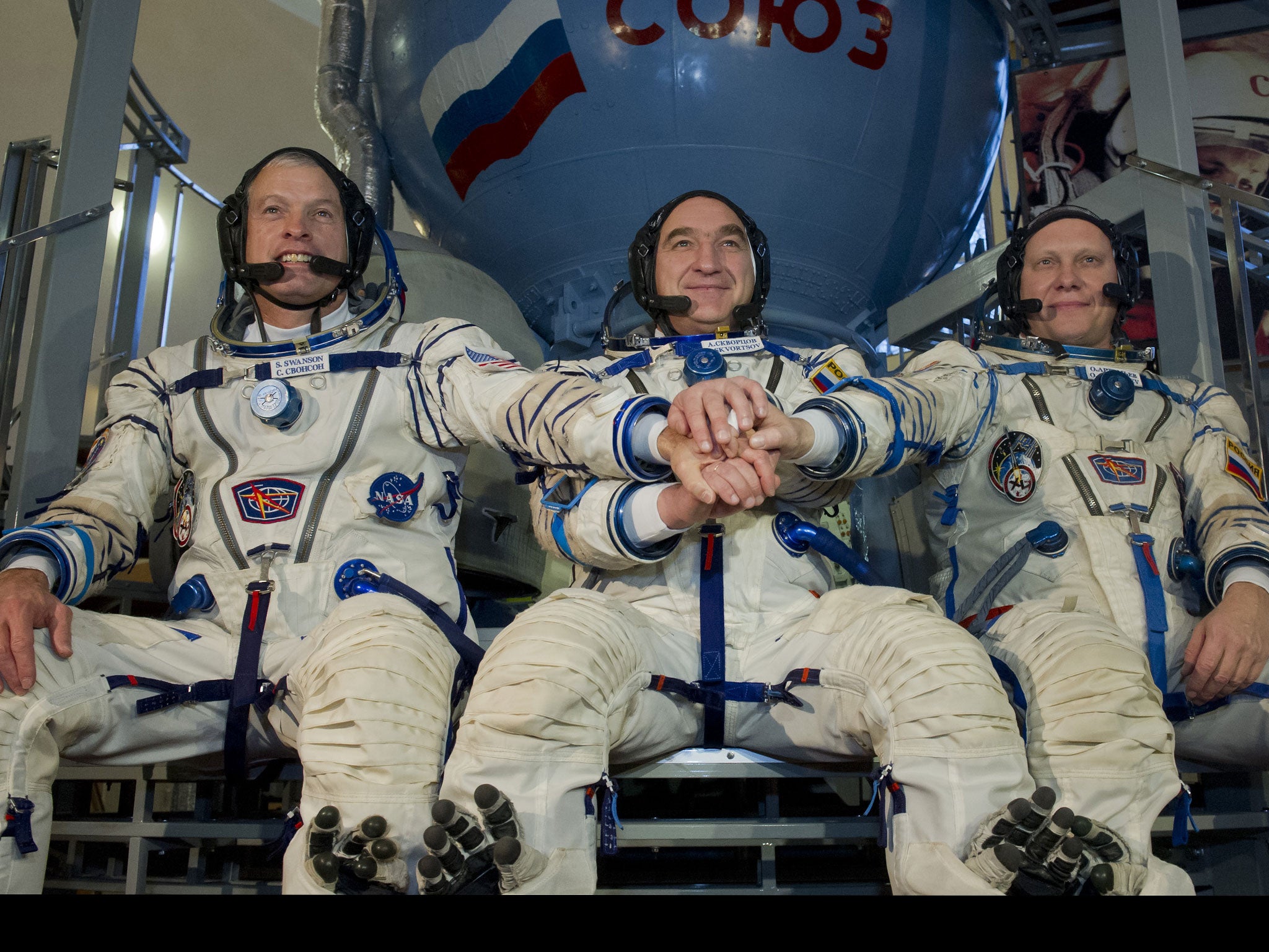 US NASA astronaut Steven Swanson (L) joins hands with Russian cosmonauts, Alexander Skvortsov (C) and Oleg Artemyev (R), in front of a mock-up of a Soyuz TMA spacecraft before their final preflight exam at the Gagarin Cosmonauts' Training Centre in Star C