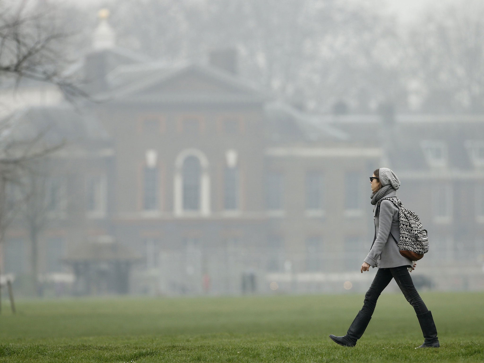 A woman strolls through Kensington Gardens amid the smog