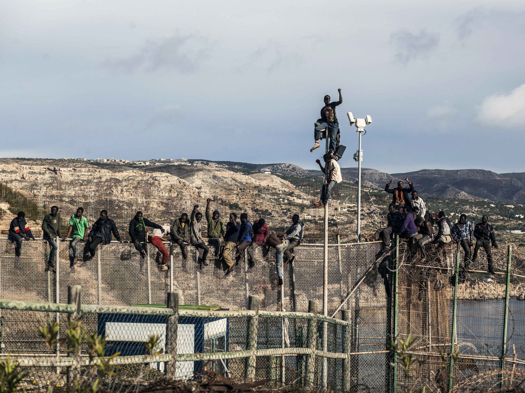 Would-be immigrants sit atop a boarder fence separating Morocco from the north African Spanish enclave of Melilla following a morning assult on the boarder in an attempt to cross into Spain