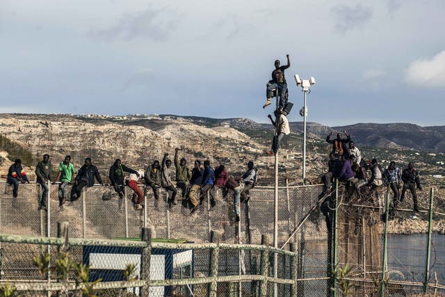 Would-be immigrants sit atop a boarder fence separating Morocco from the north African Spanish enclave of Melilla following a morning assult on the boarder in an attempt to cross into Spain 