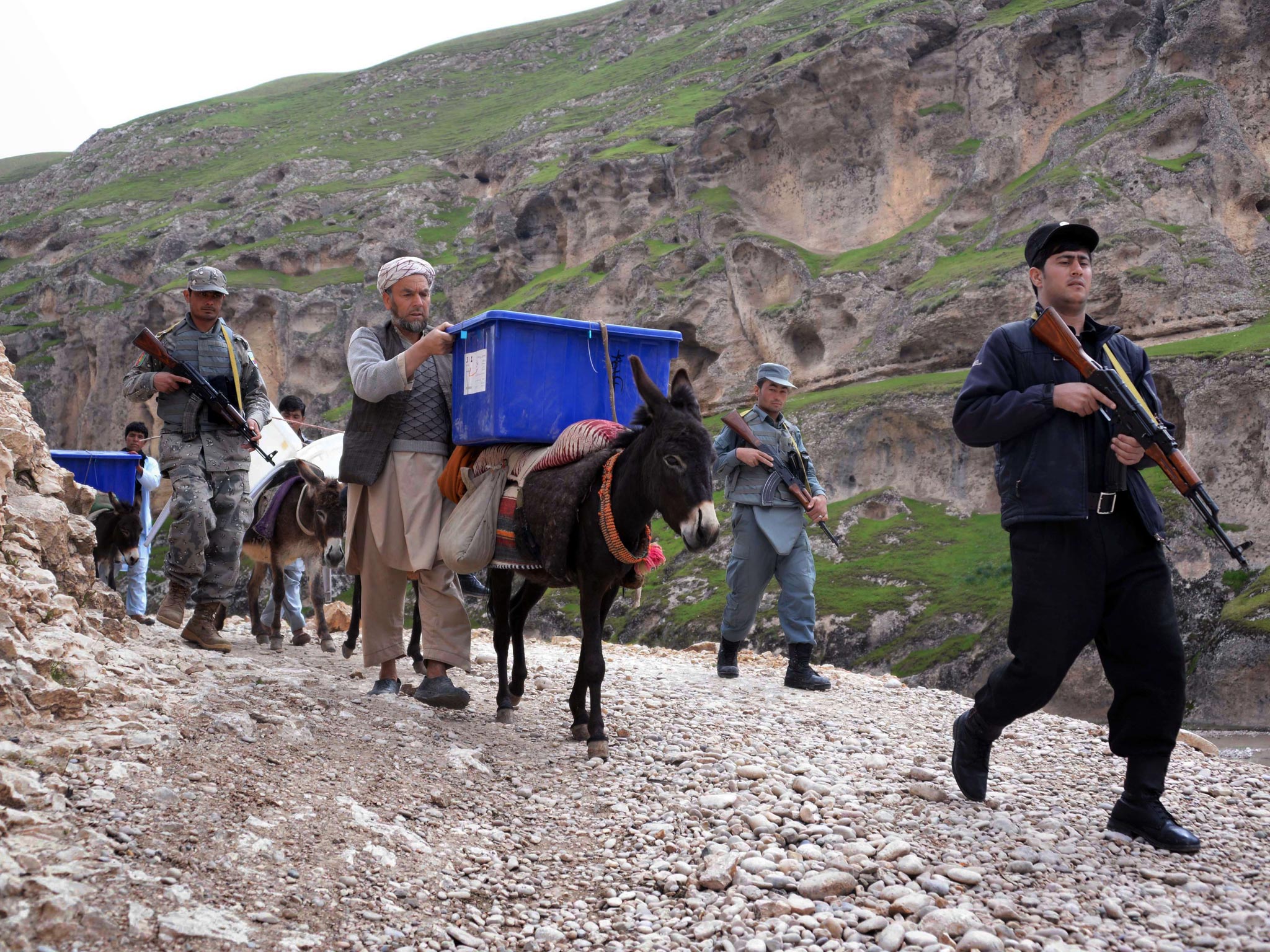 Afghan election workers are escorted by armed policemen as they transport election materials and ballot boxes to remote polling stations in Balkh Province this week