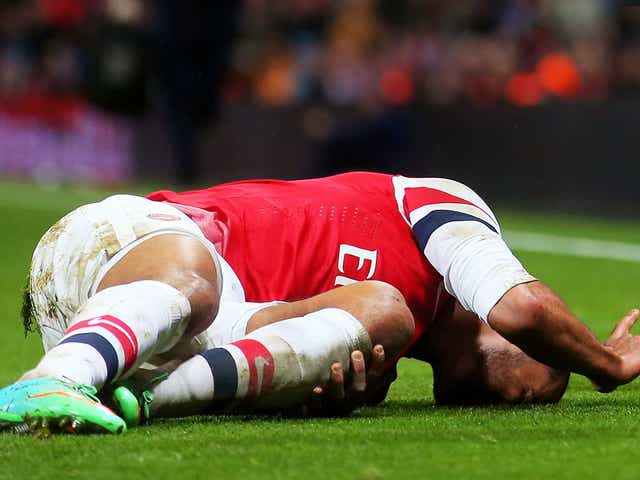 Walcott lies stricken after sustaining the injury in an FA Cup game against Spurs