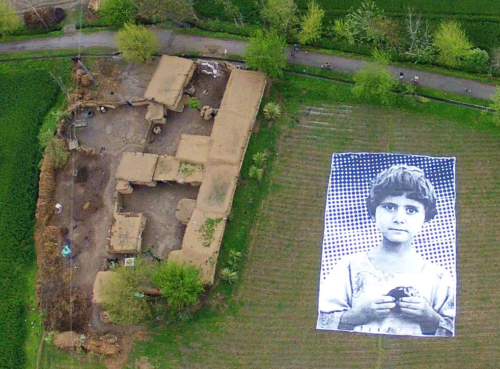 A poster bearing the image of a Pakistani girl whose parents, lawyers say, were killed in a drone strike, lies in a field at an undisclosed location in the northwestern Khyber-Pakhtunkhwa province. A group of artists in Pakistan are hoping to generate "em