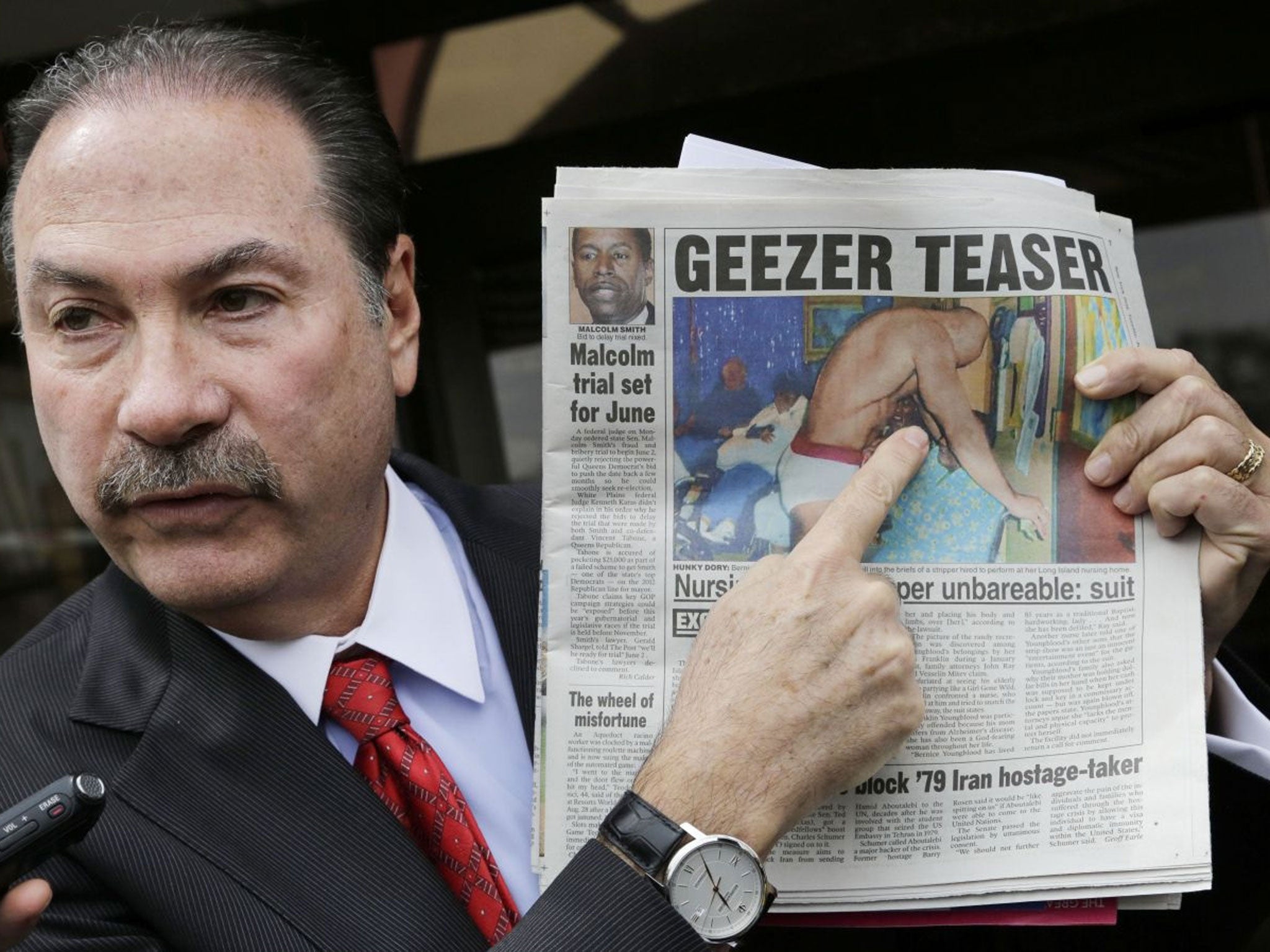 Attorney Howard Fensterman, representing the East Neck Nursing and Rehabilitation Center, points to a newspaper article about the nursing home during a news conference