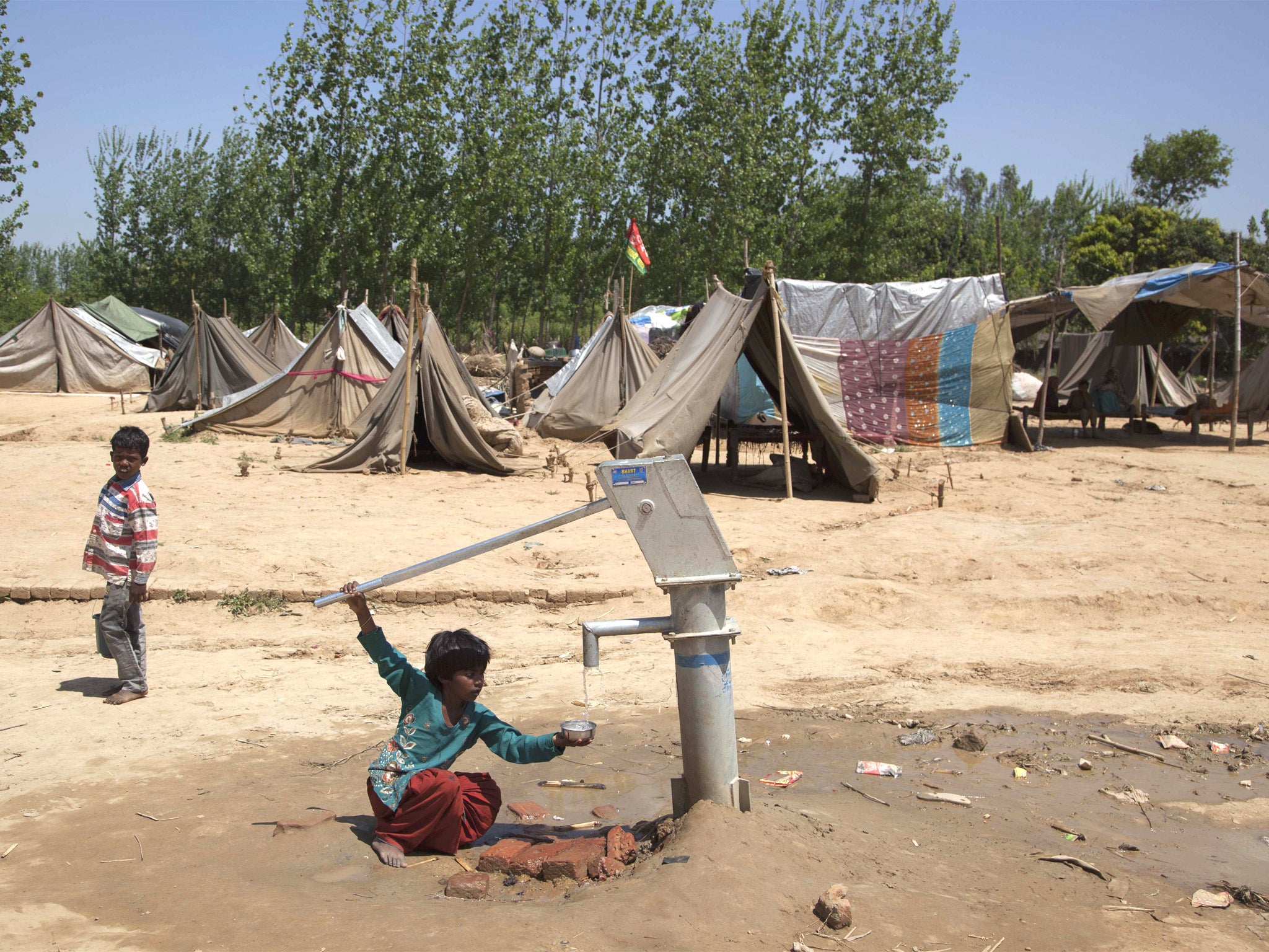 A girl pumps water at a camp in Kutba, scene of much of last year’s violence