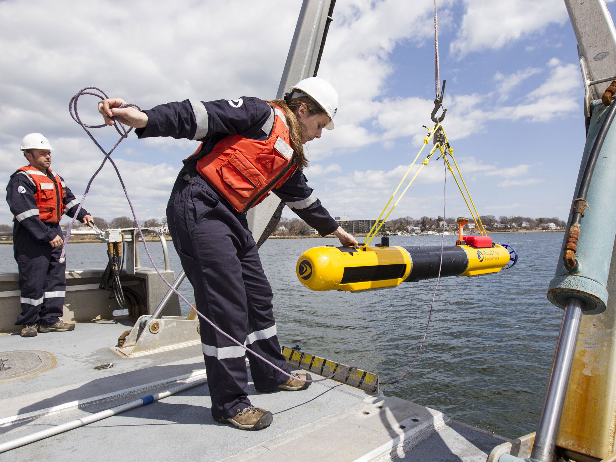 A submarine built by Bluefin Robotics is lowered into the water by systems engineer Cheryl Mierzwa in Quincy to help locate the missing Malaysian Airlines Flight 370