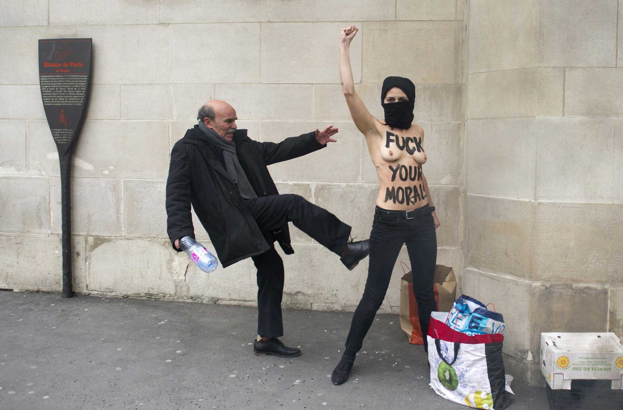 Veiled threat: a topless activist from Femen under attack in front of the Great Mosque of Paris last year