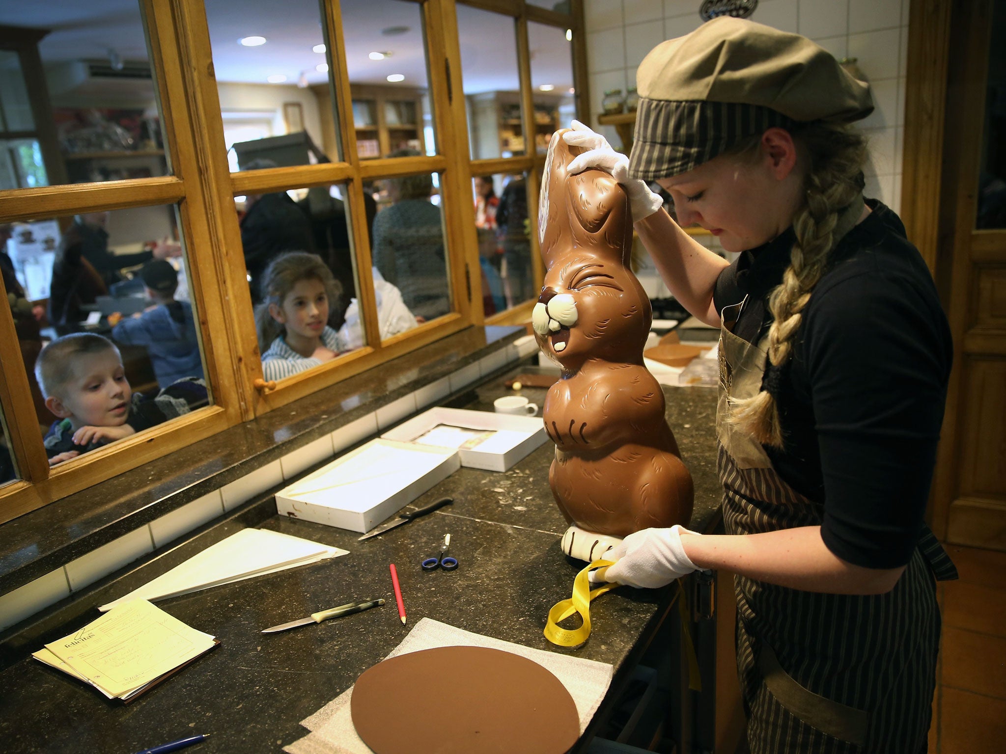 Children from a Polish tour group watch as employee Sandra Jaeckel prepares to take away a giant chocolate Easter bunny after showing it to them at Confiserie Felicitas chocolates maker in Hornow