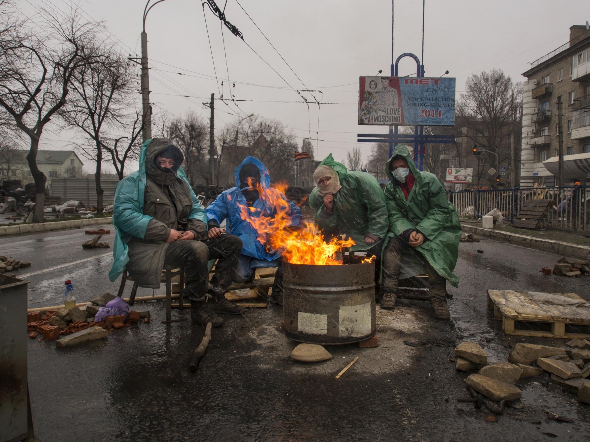 Pro-Russian activists warm themselves at a bonfire next to barricades in front of an entrance to the Ukrainian regional office of the Security Service in Luhansk