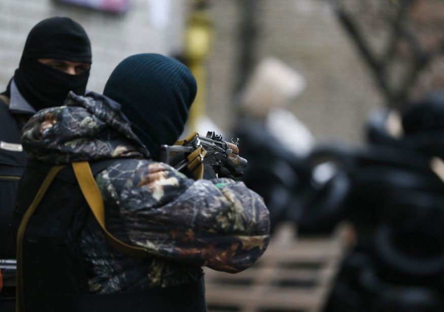 A pro-Russian armed man checks the gun sight of his weapon next to a barricade in front of the police headquarters in Slovyansk