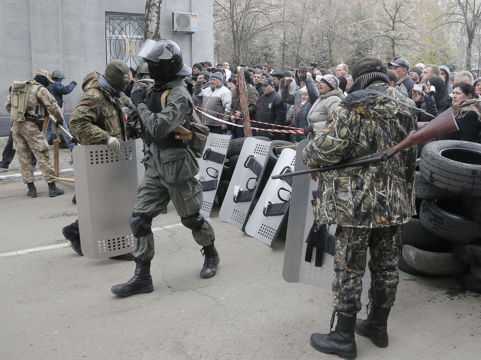 Pro-Russian activists occupy the police station carrying riot shields as people watch on, in the eastern Ukraine town of Slovyansk