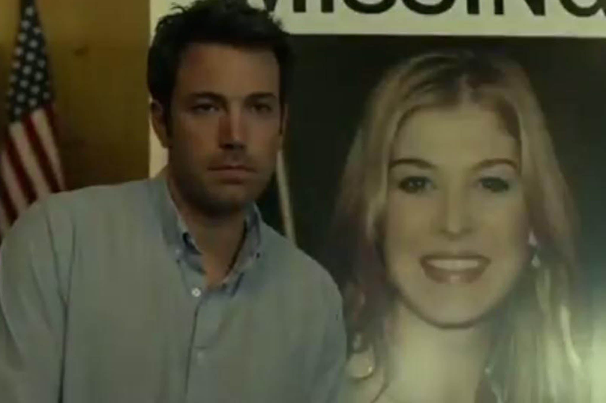 Ben Affleck as Nick Dunne, seated next to a picture of his missing wife Amy, played by Rosamund Pike