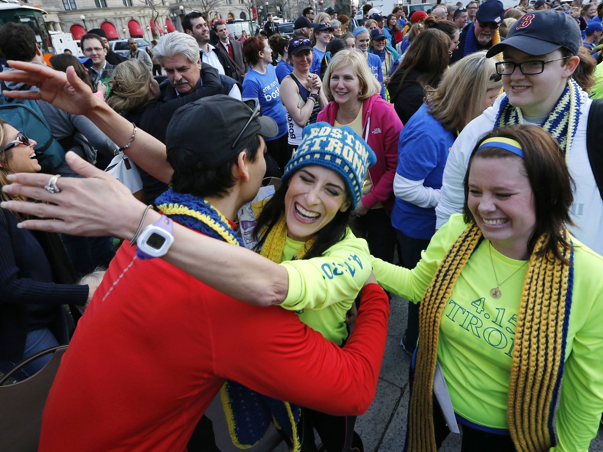 Boston Marathon bombing survivors Doug Julian (L) and his partner Lynn Crisci (C) hug as fellow survivor Shannon Silvestri (R) looks on in Boston. The trio, joined by other survivors, family members and supporters met up with participants of a cross country charity relay that began in California and ended at the finish line of the Boston Marathon