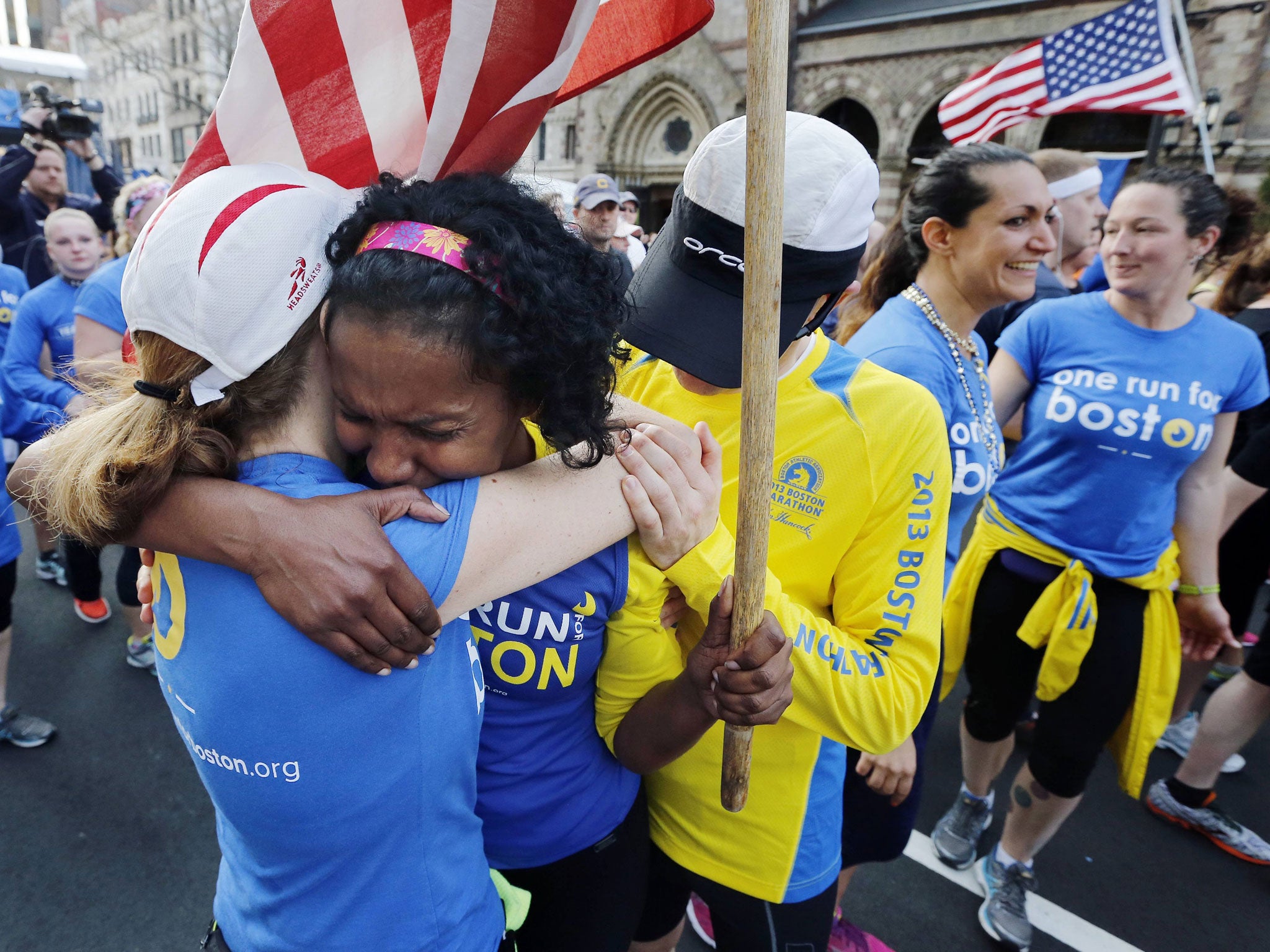 Rosa Evora (C) hugs a fellow participant in a cross country relay that began in California and ended at the Boston Marathon finish line in Boston