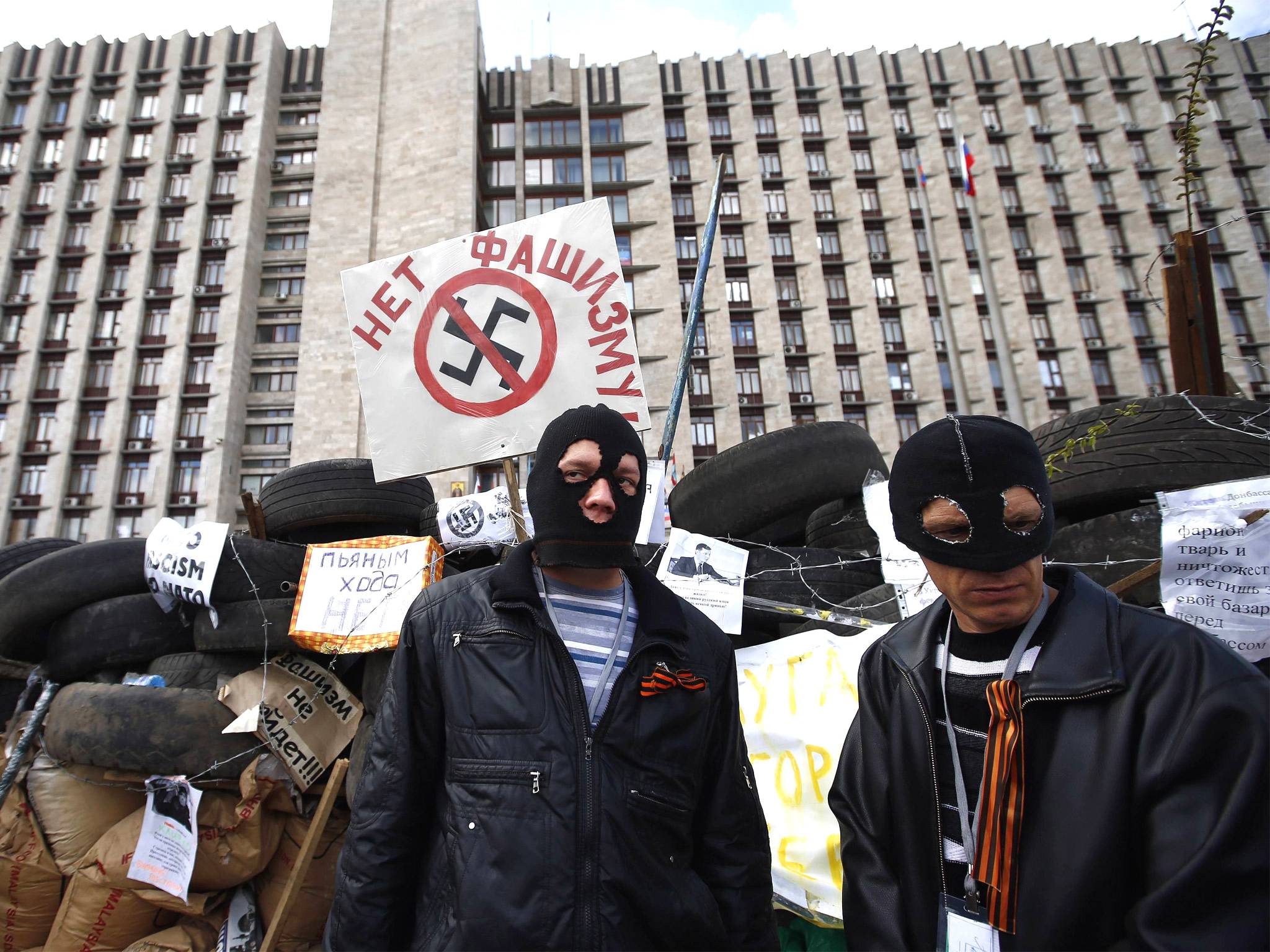 Masked pro-Russia separatists stand guard at a barricade outside a government building in Donetsk