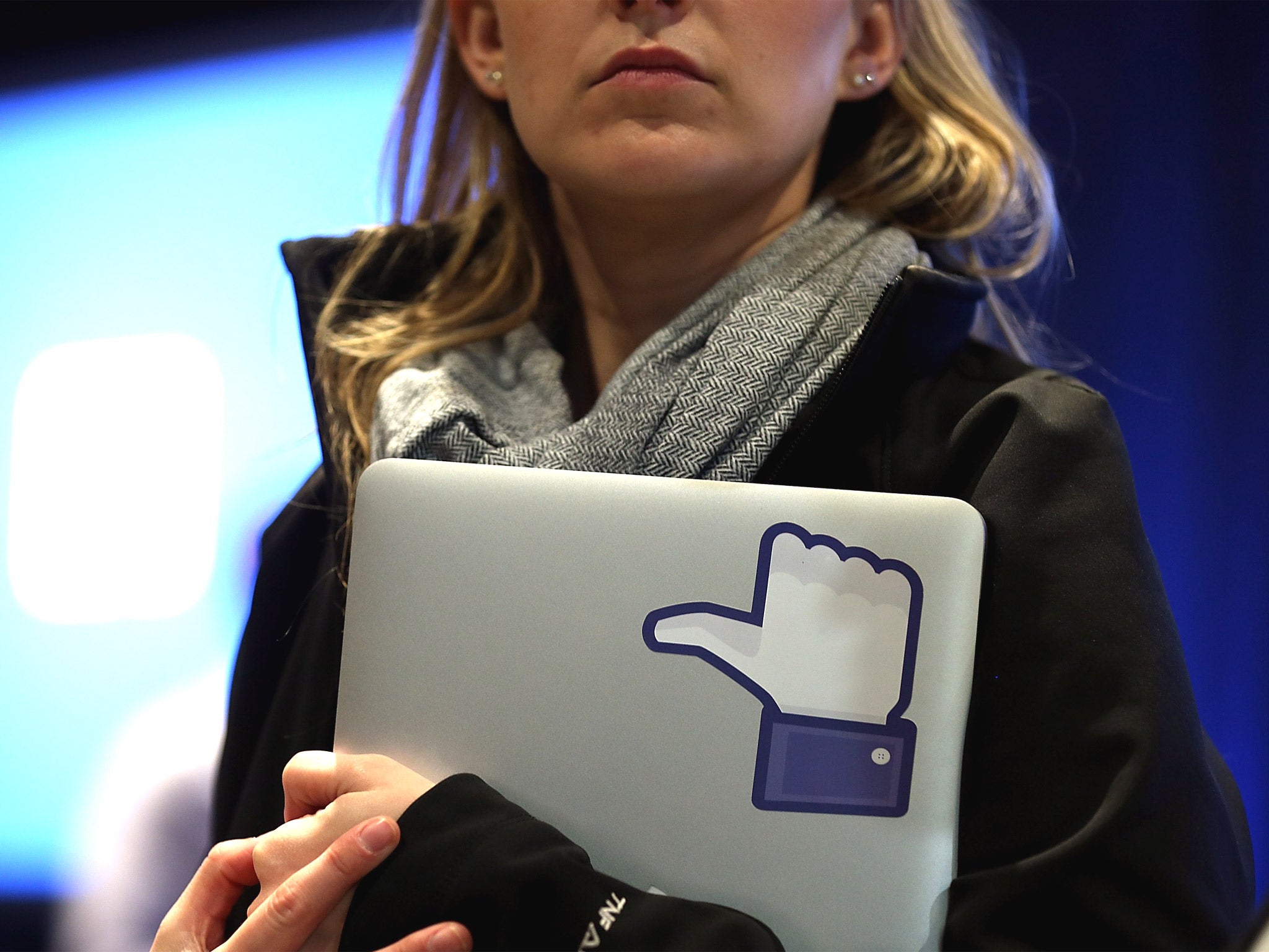 A woman holds a laptop with the 'Like' symbol on its screen