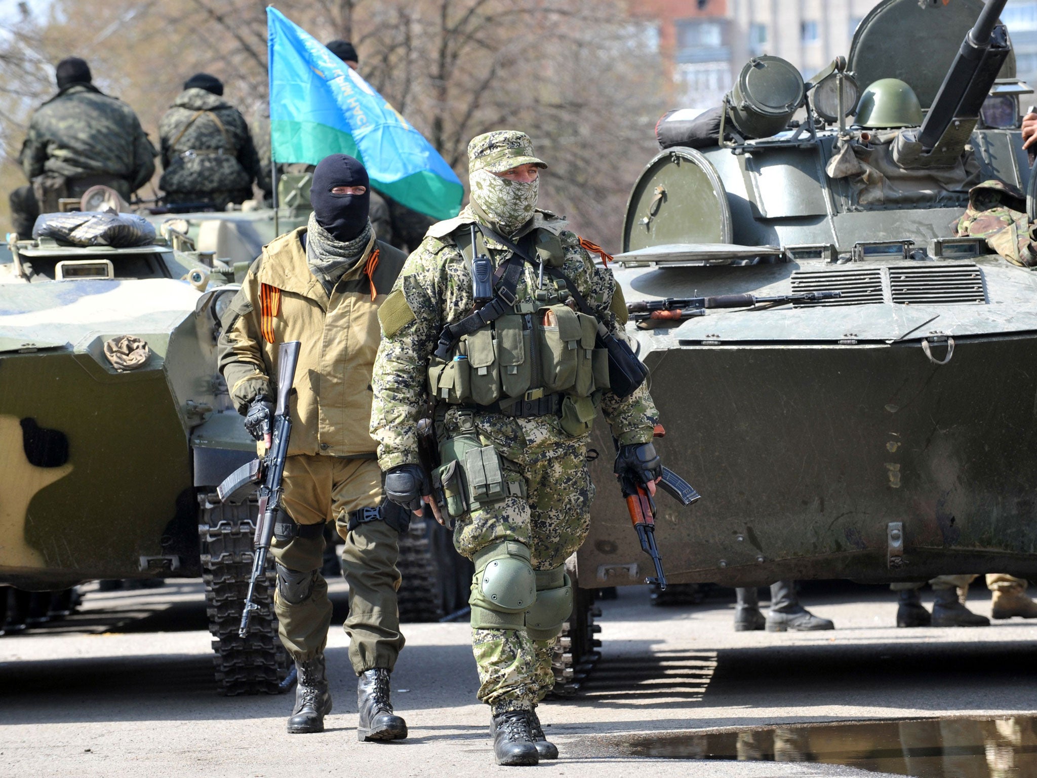 Armed men wearing military fatigues gather by Armoured Personnel Carriers (APC) as they stand guard outside the regional state building seized by pro-Russian separatists in the eastern Ukrainian city of Slavyansk