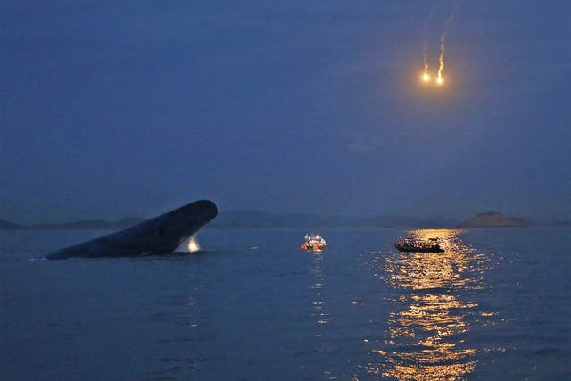 South Korean ferry 'Sewol' is seen sinking in the sea off Jindo, as lighting flares are released for a night search