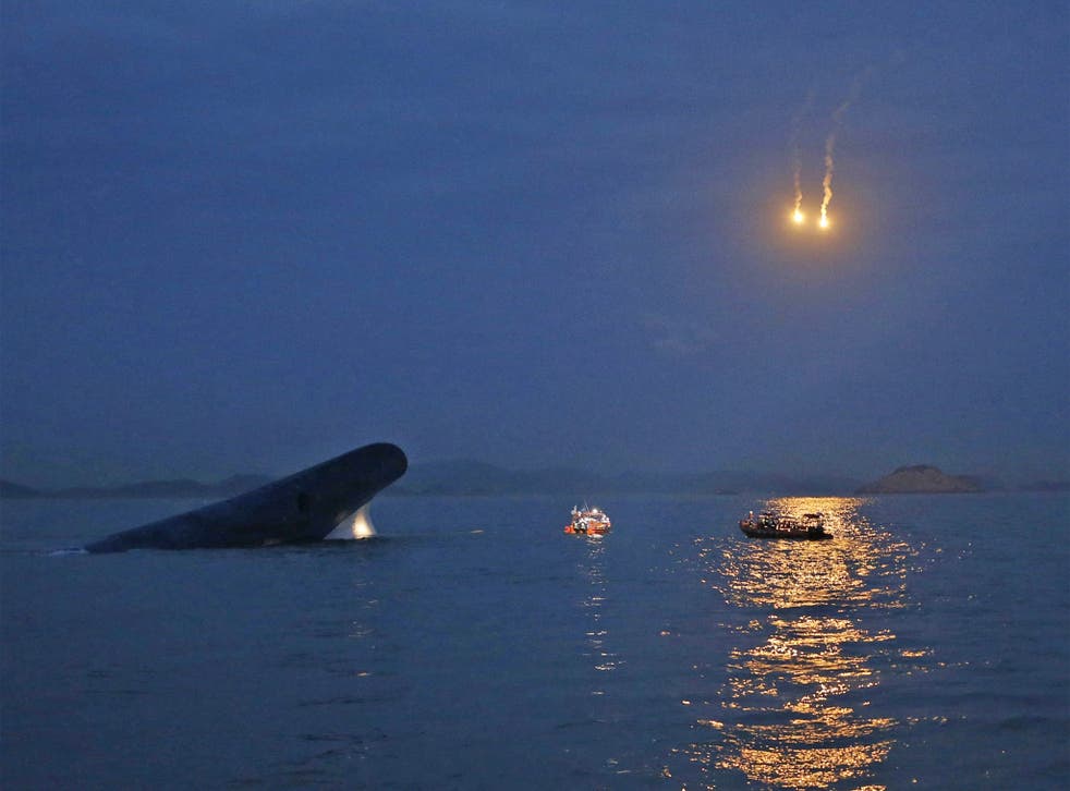South Korean ferry 'Sewol' is seen sinking at the sea off Jindo, as lighting flares are released for a night search